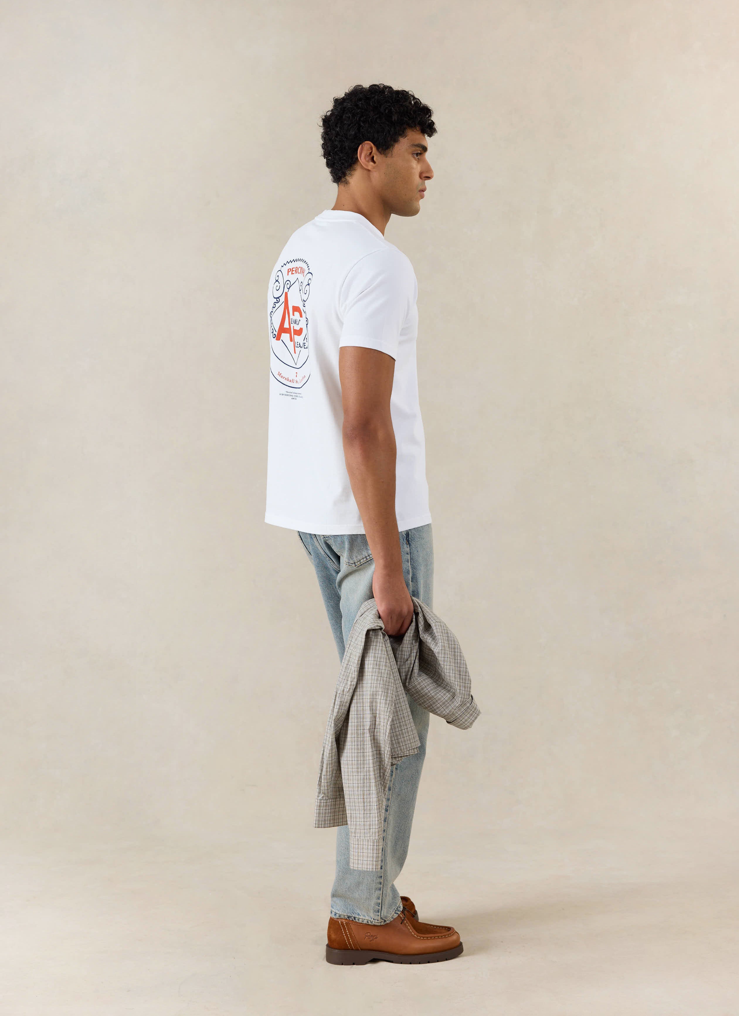 The white Cyril T Shirt from Percival in organic cotton, featuring a graphic back print and styled with light blue jeans.