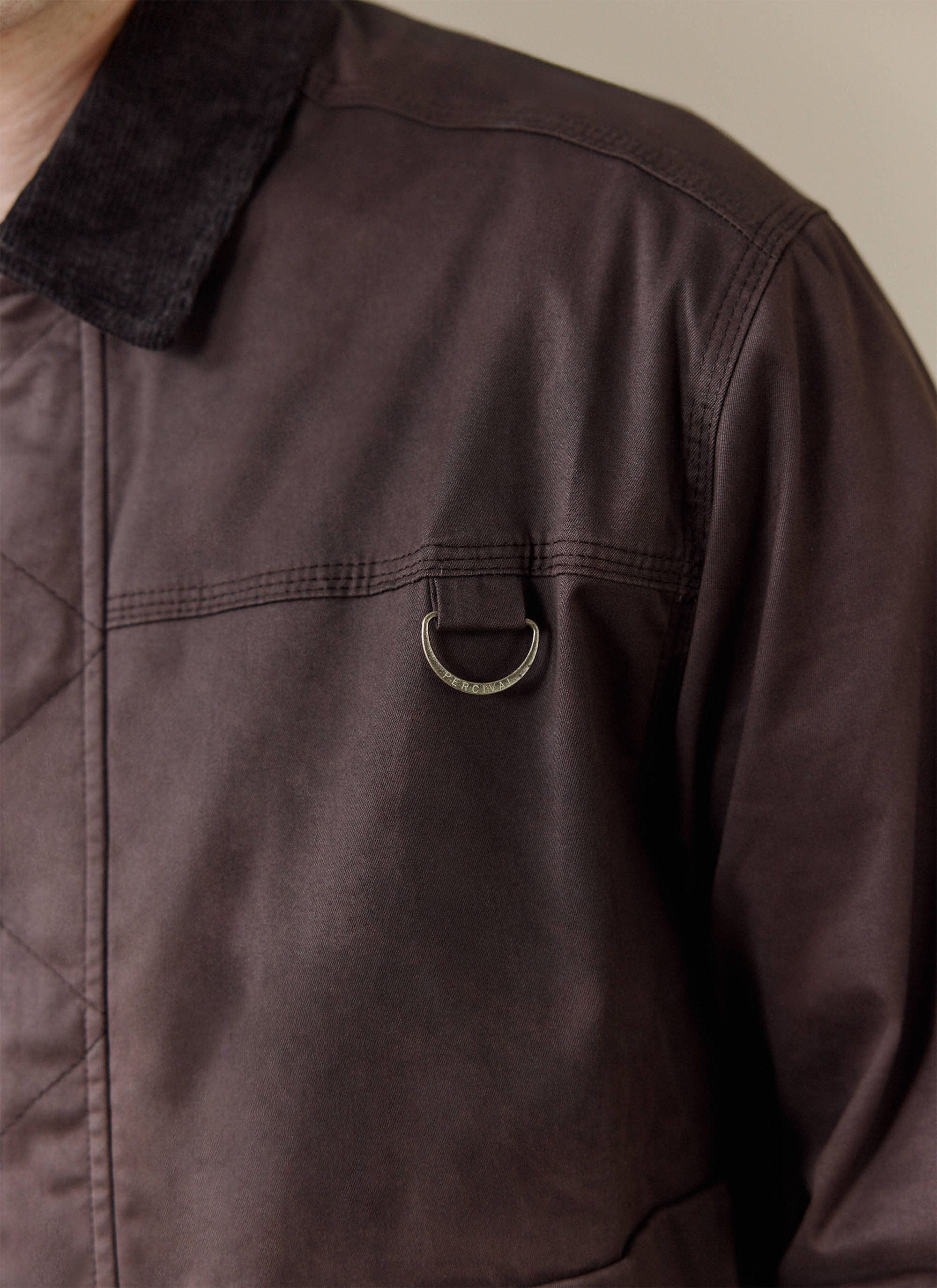 Close-up of the espresso brown Percival wax zip jacket showing the chest pocket detail and D-ring.