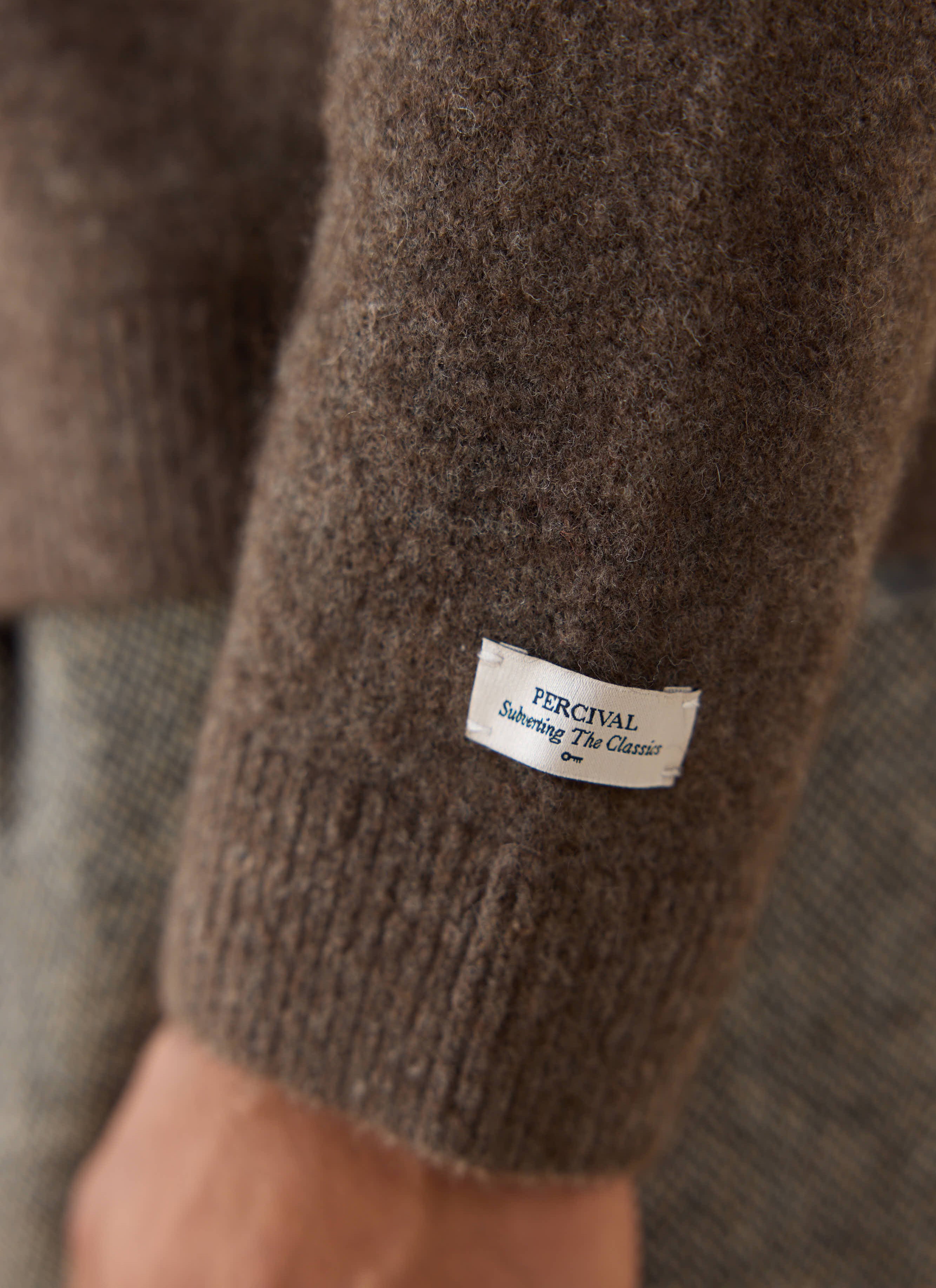 Close-up of the brown yak wool sleeve on the Percival cardigan, featuring the white woven brand label.