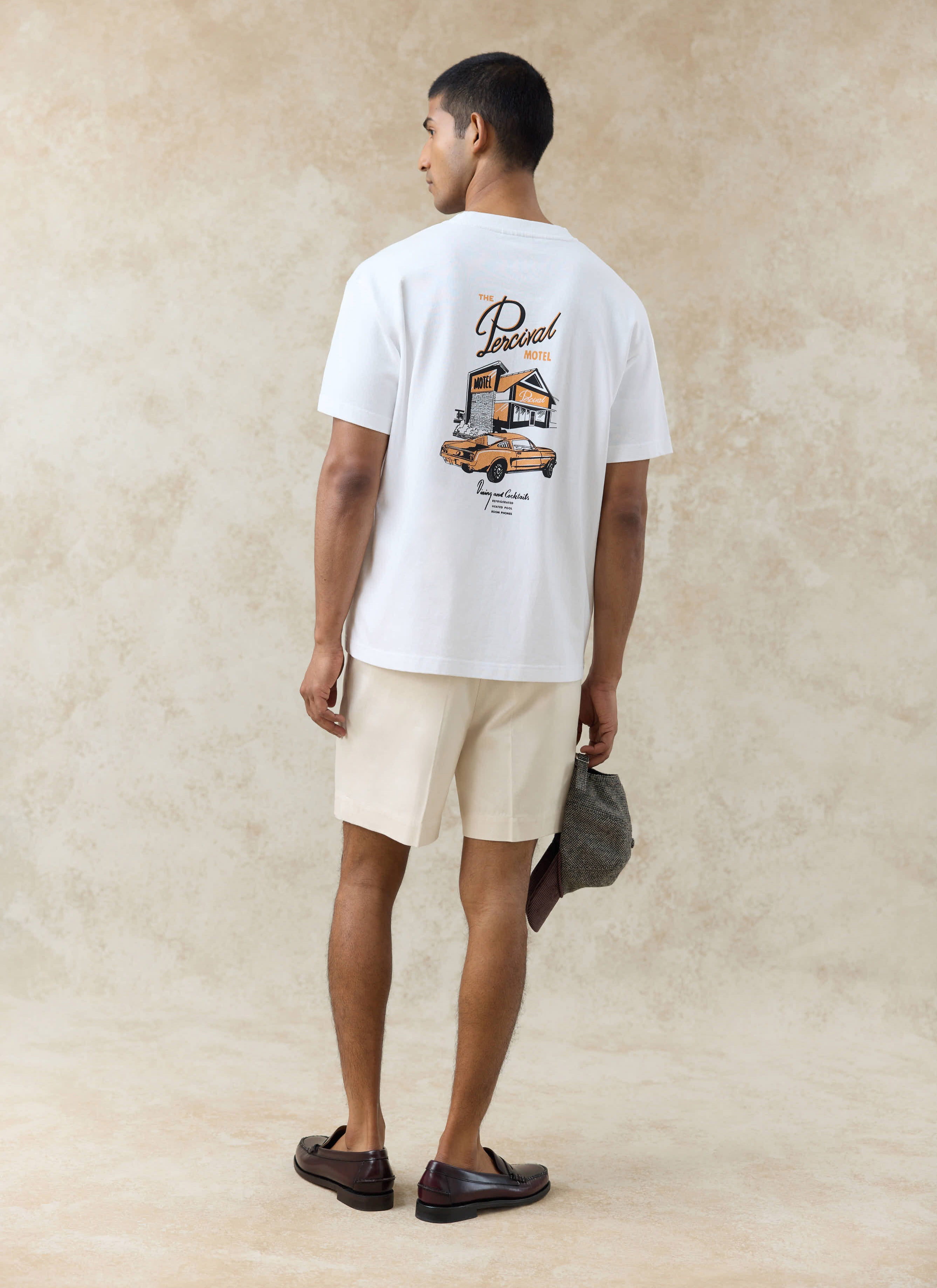 Back view of the white Percival Alistair oversized T-shirt with motel graphic and cream Blake pleated cotton shorts.