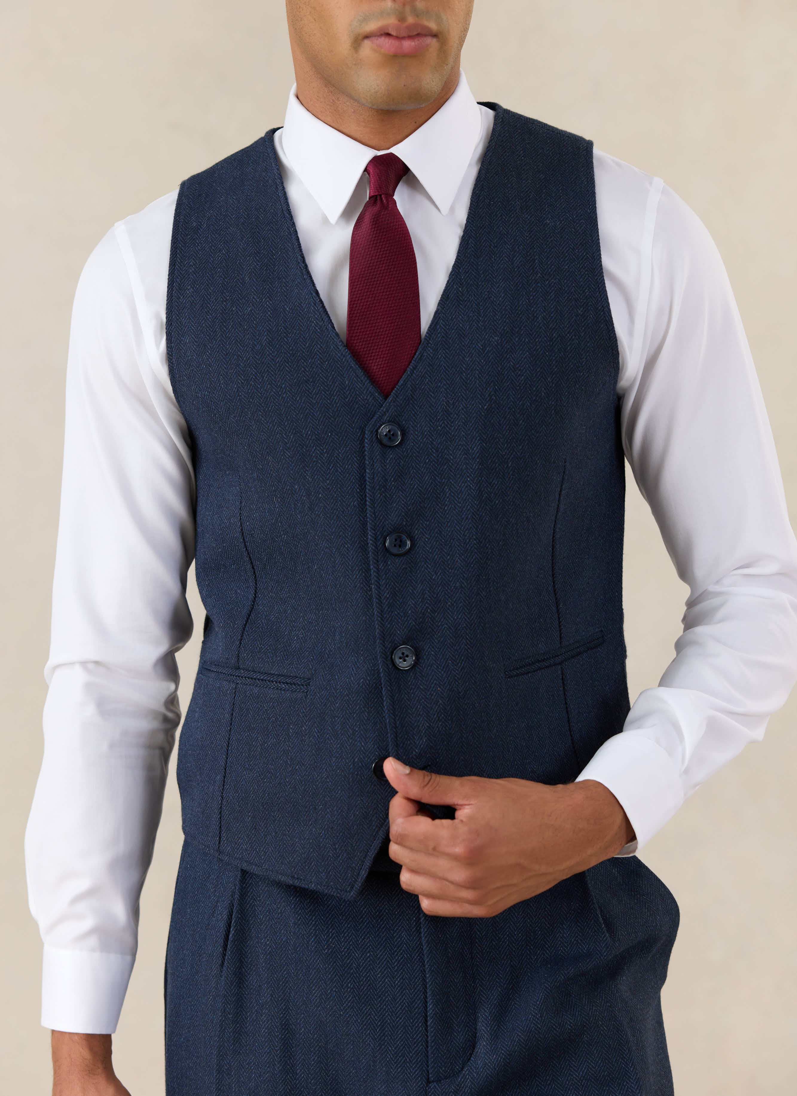 Percival Navy Herringbone Wool Stanley Tailored Waistcoat styled with a white shirt and a textured burgundy tie.
