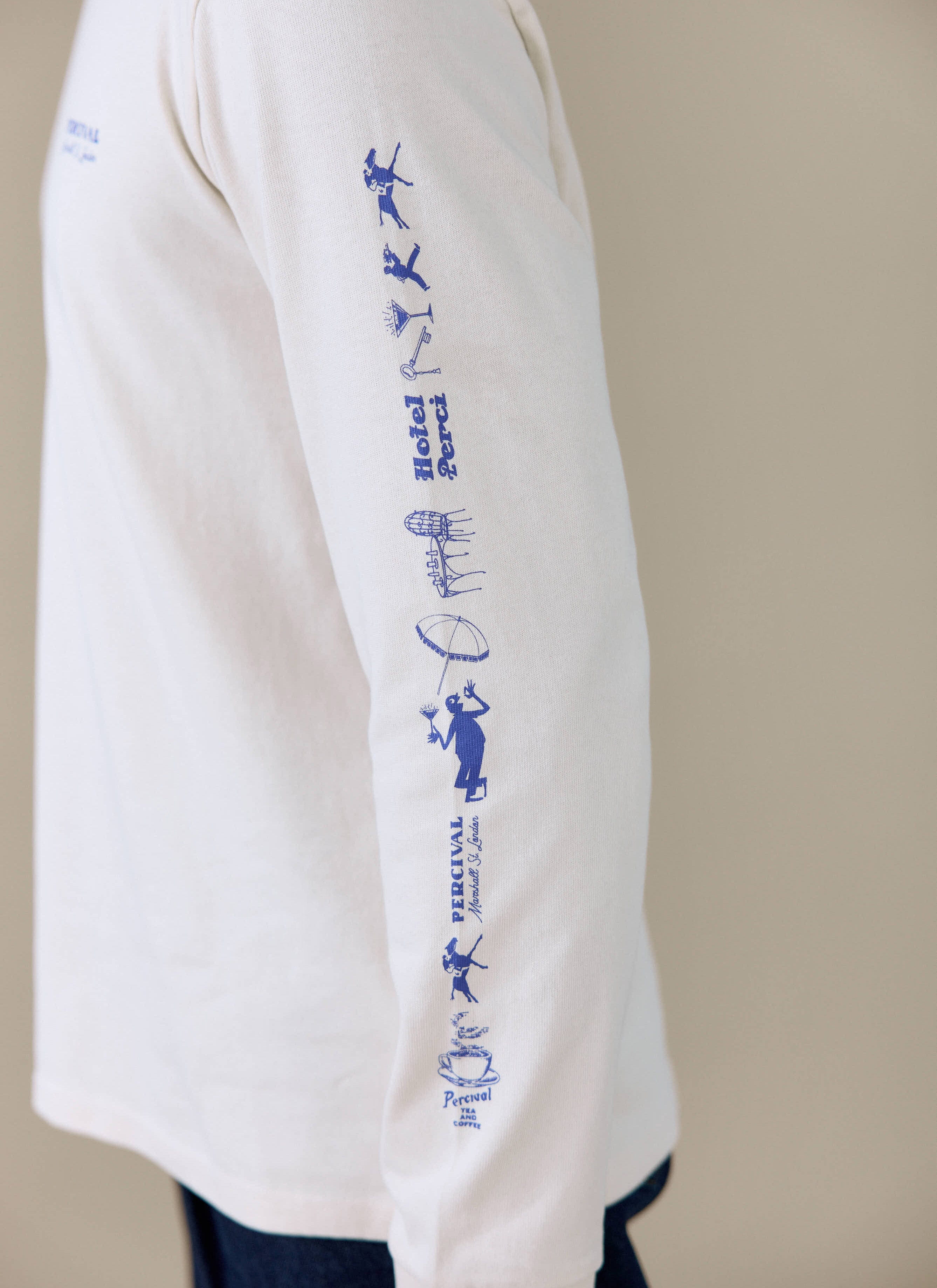 Close-up of the blue graphic print on the sleeve of the Percival Harlow Fine Wines long sleeve T-shirt in cream.