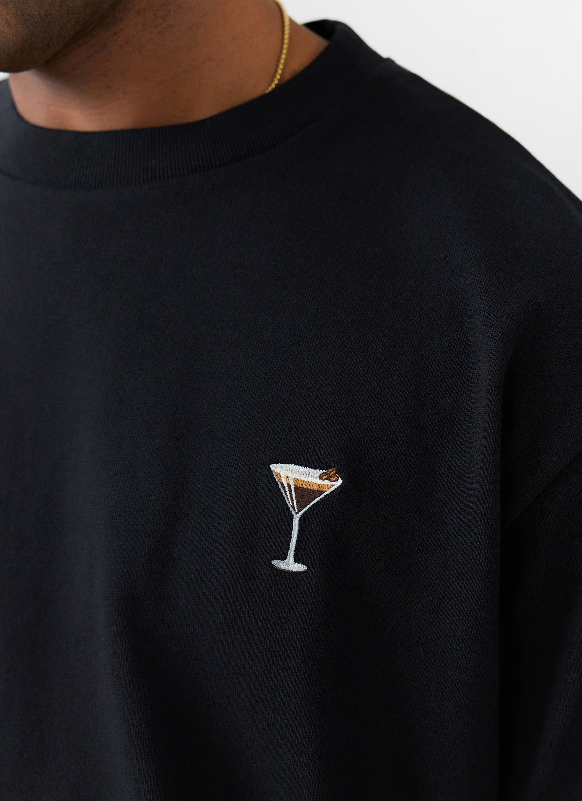 Close-up of a model wearing the Percival Espresso Martini t-shirt in black, showing the cocktail embroidery.