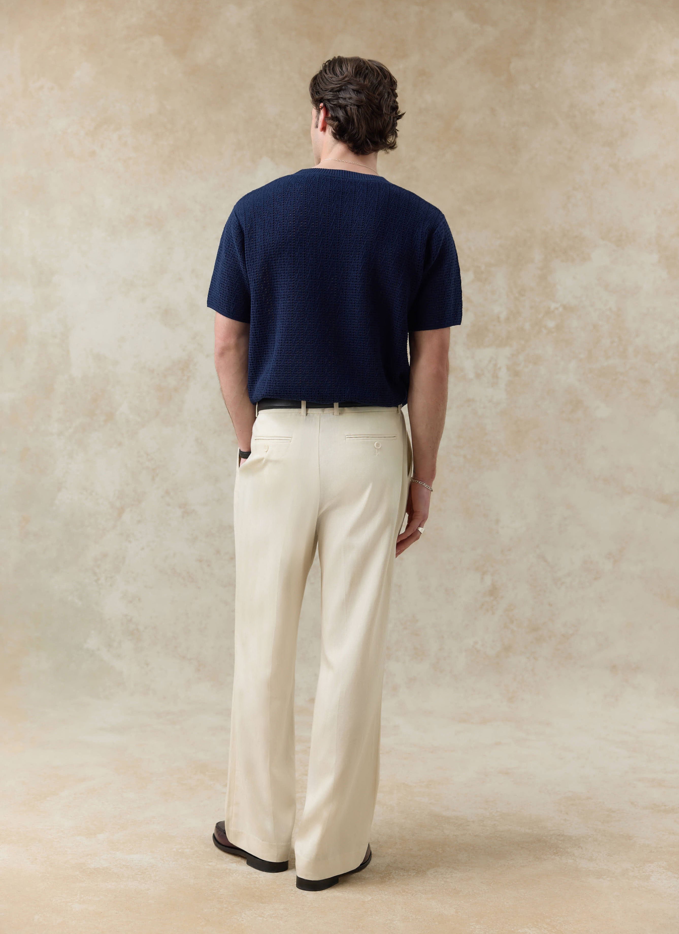 The navy Percival Siena Knitted T Shirt in textured cotton, shown from behind on a model with light trousers.