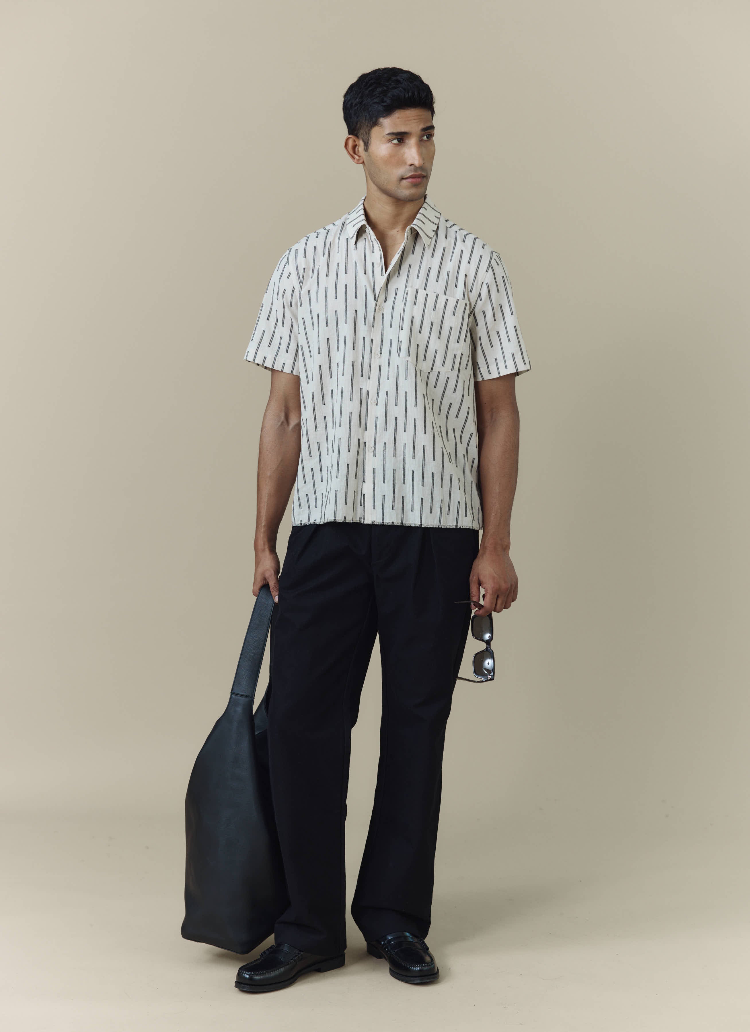 A model wears the Percival Nancy Boxy Shirt in ecru with black jacquard stripes, styled with black trousers and loafers.
