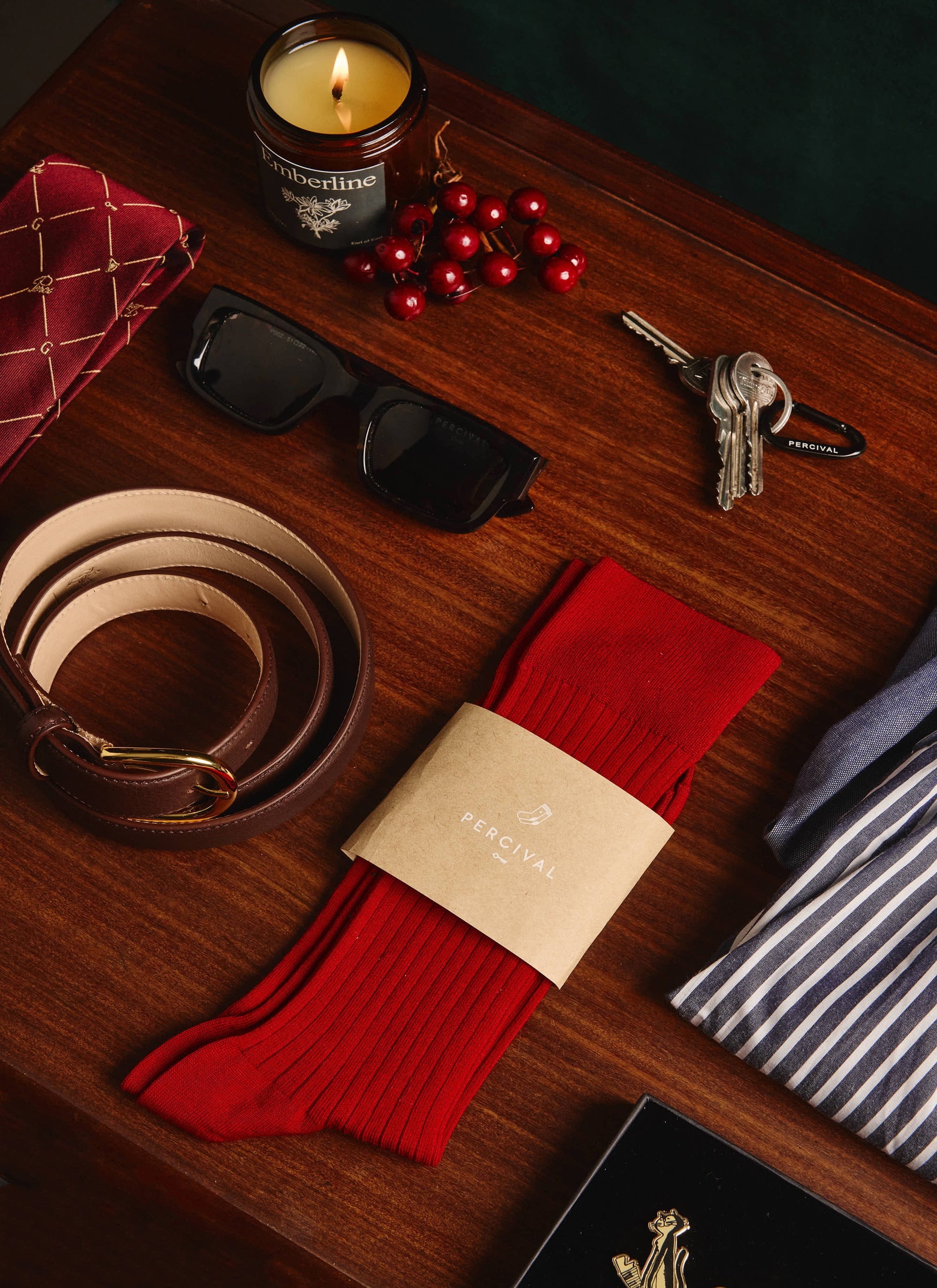 The red ribbed Loafer Dress Socks by Percival, displayed on a wooden table among other classic men's accessories.
