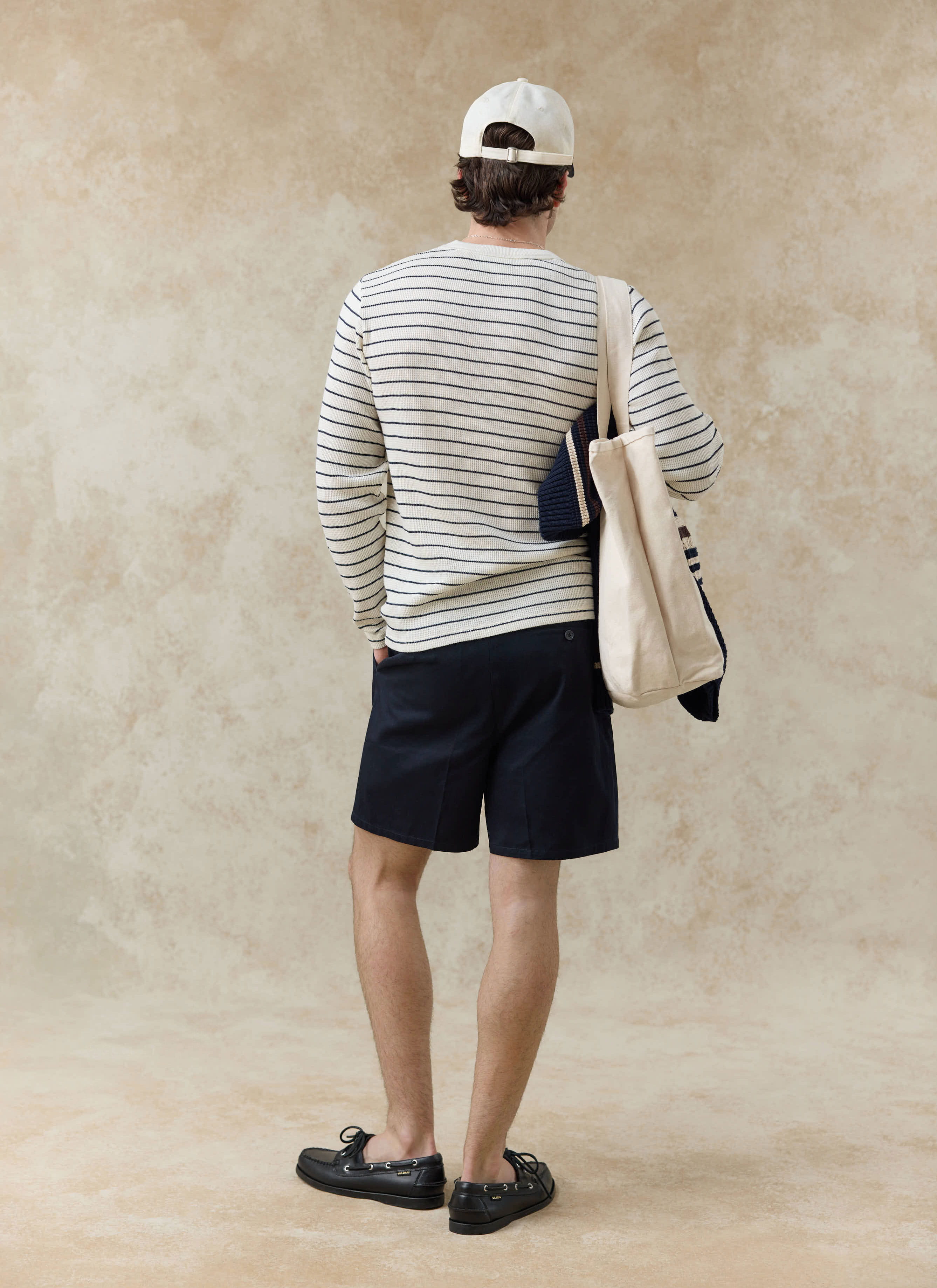 Percival Ernie Waffle Long Sleeve T Shirt in cream stripe, viewed from the back with navy shorts and a canvas tote.