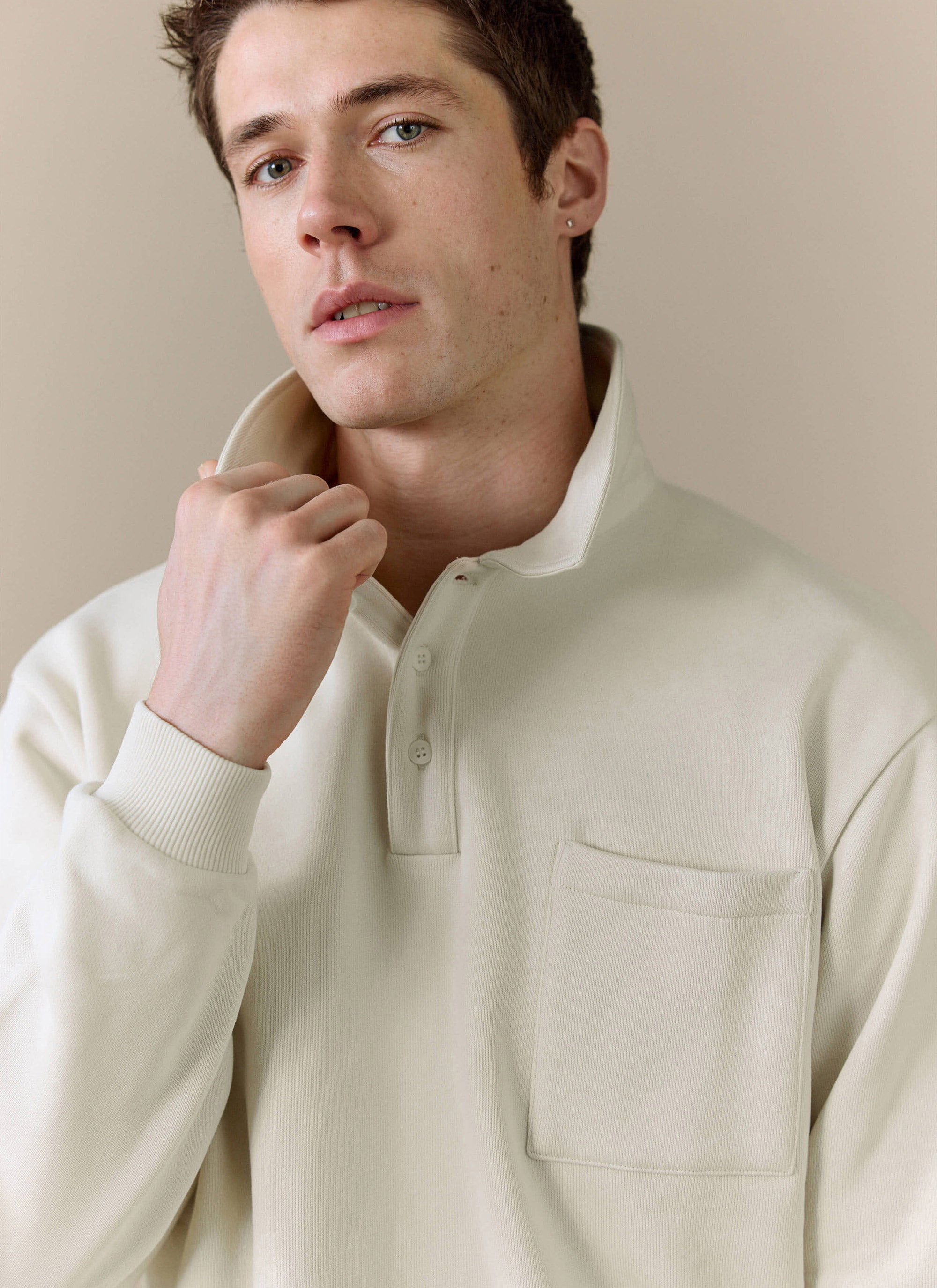 Close-up of a model wearing the Percival Dudley Boxy Sweatshirt in ecru, showing the collared neckline and chest pocket.