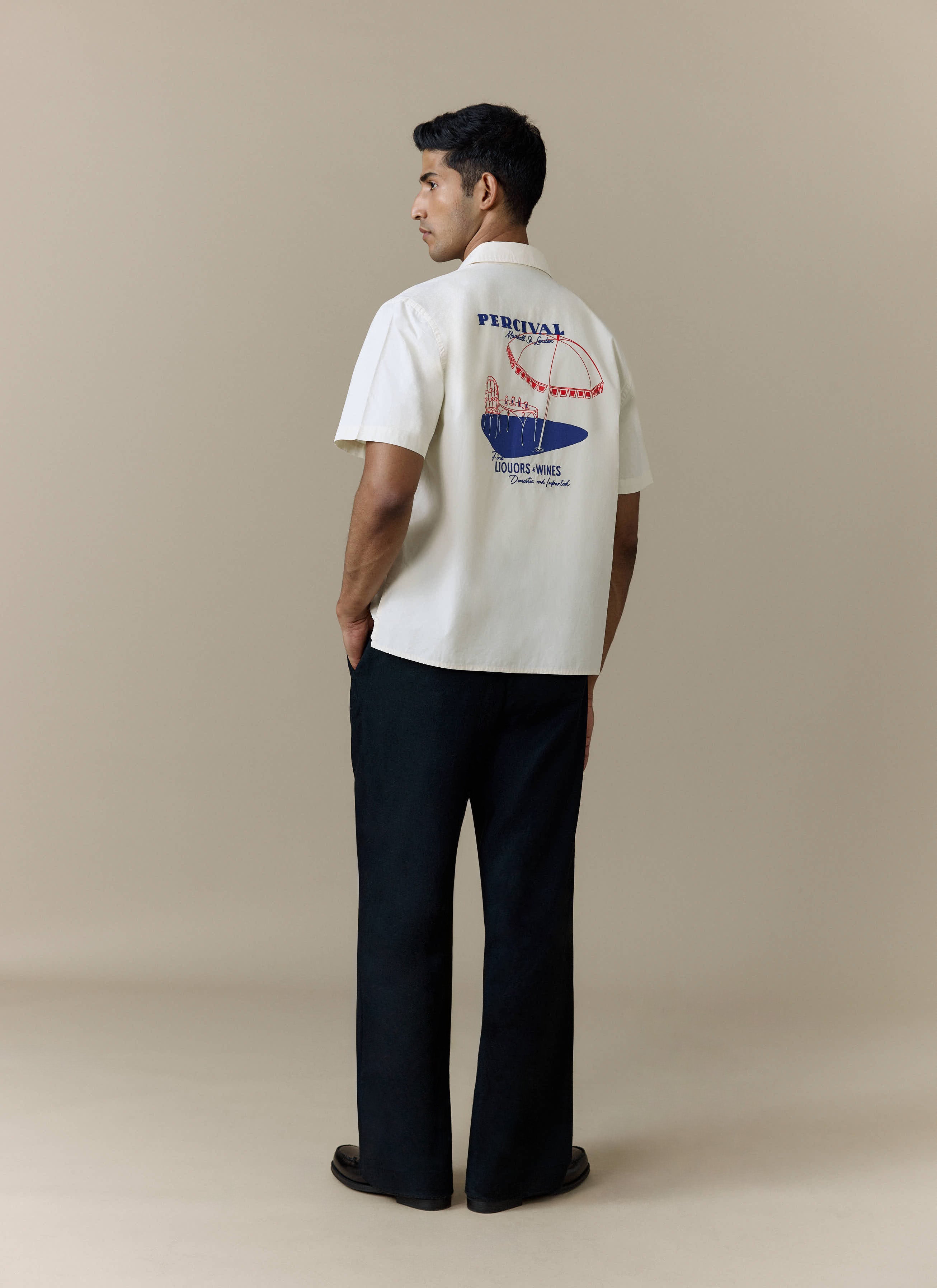 A model wears the Percival Harlow Boxy Shirt in ecru, shot from behind to showcase the custom back illustration.