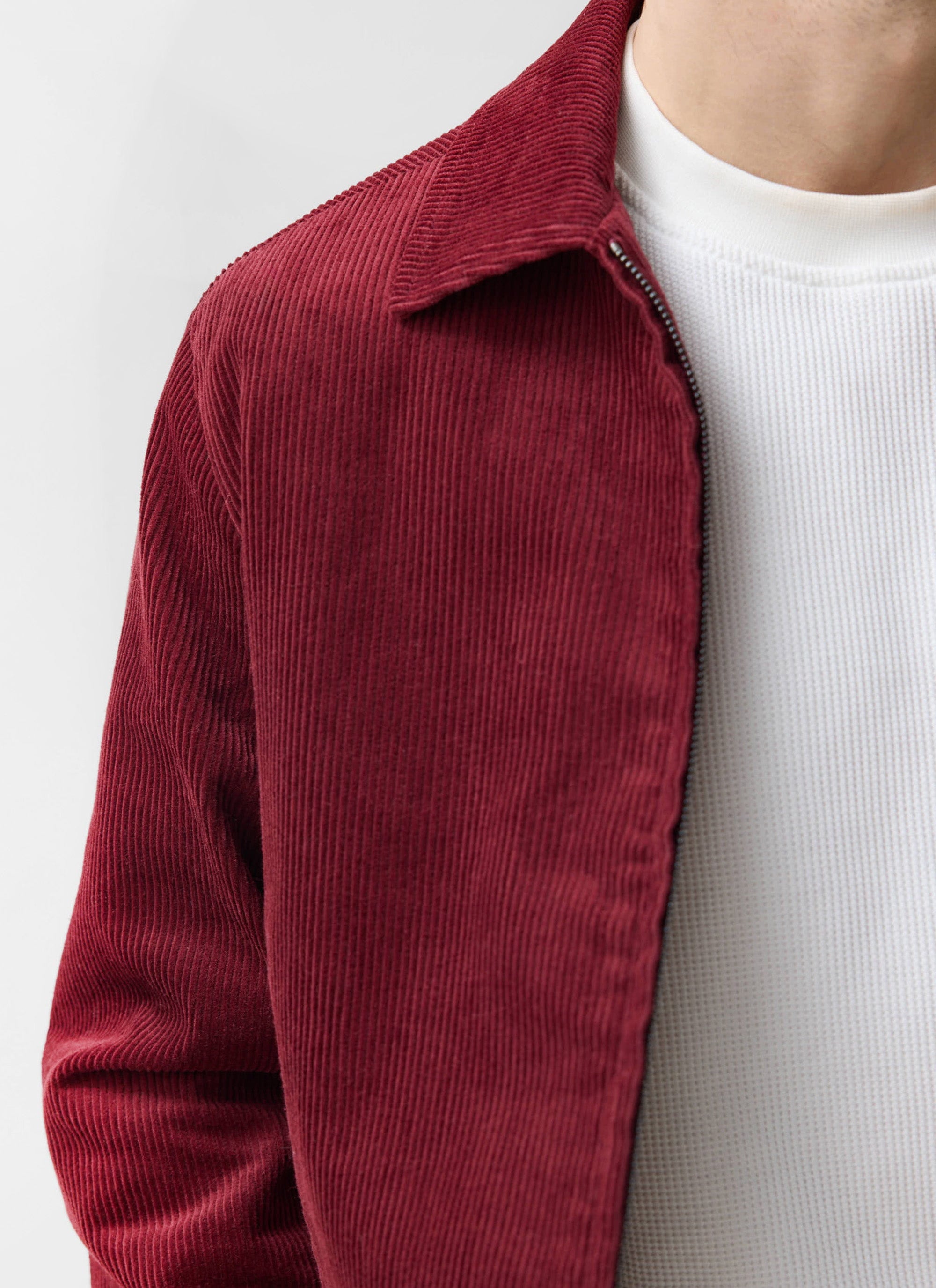 A close-up of the Percival Marcel Cord Jacket in burgundy, showing the heavy wale corduroy texture and zip detail.