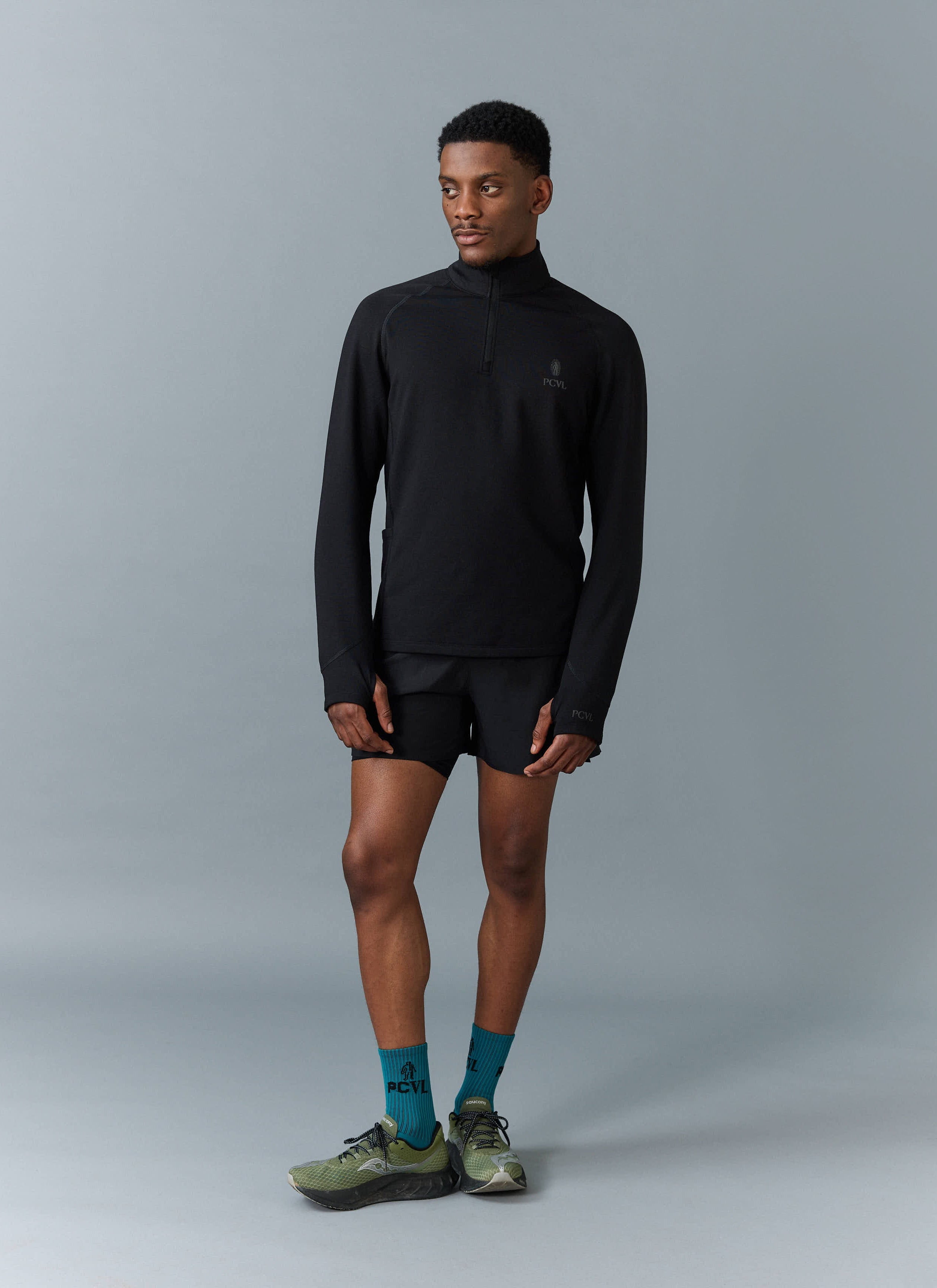 Full length shot of a male model wearing the black PCVL Base Layer Quarter Zip jacket from Percival.