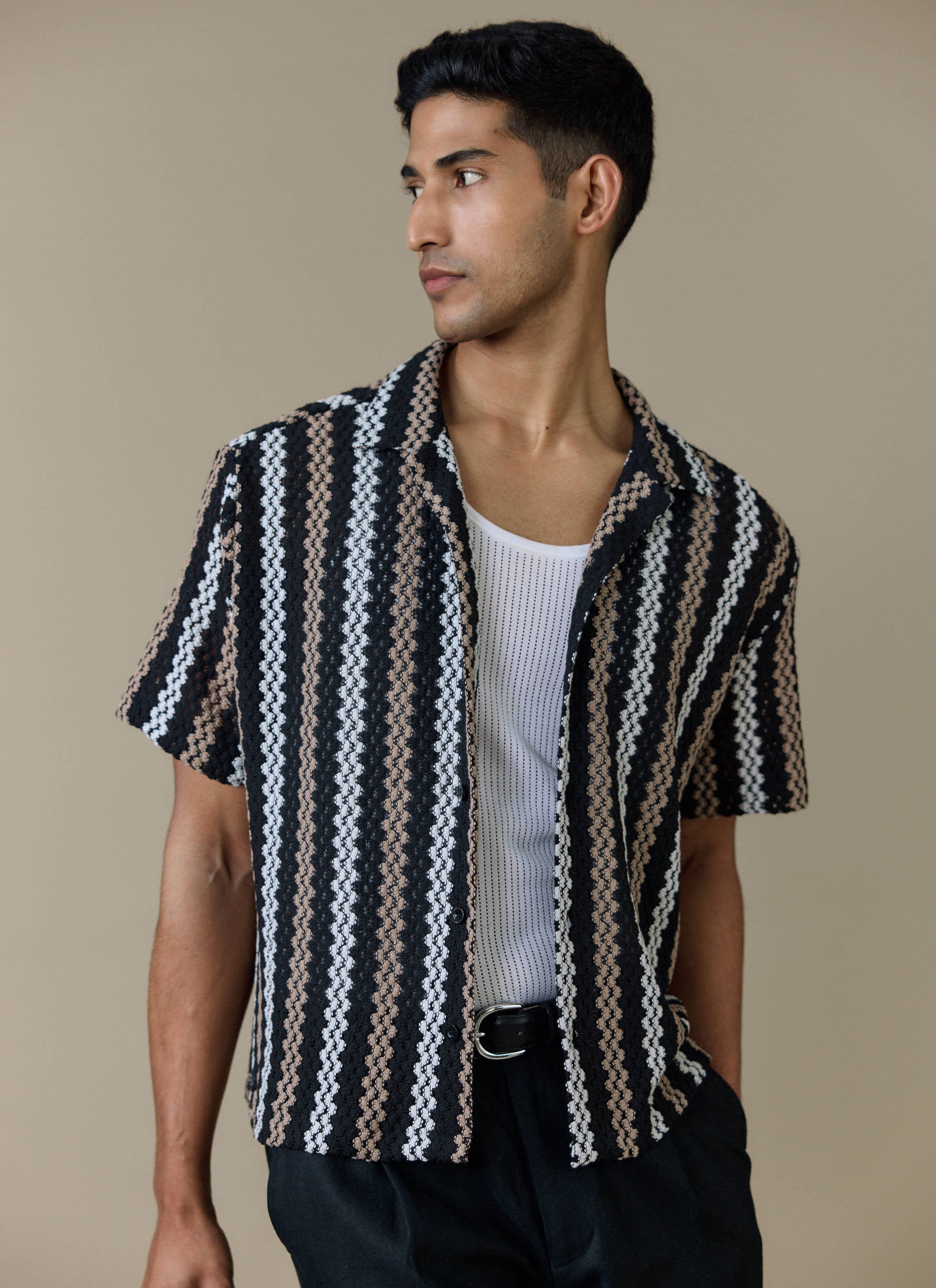 Model wearing the Percival Wade Crochet Boxy Shirt in black with textured stripes, styled open over a white ribbed vest.