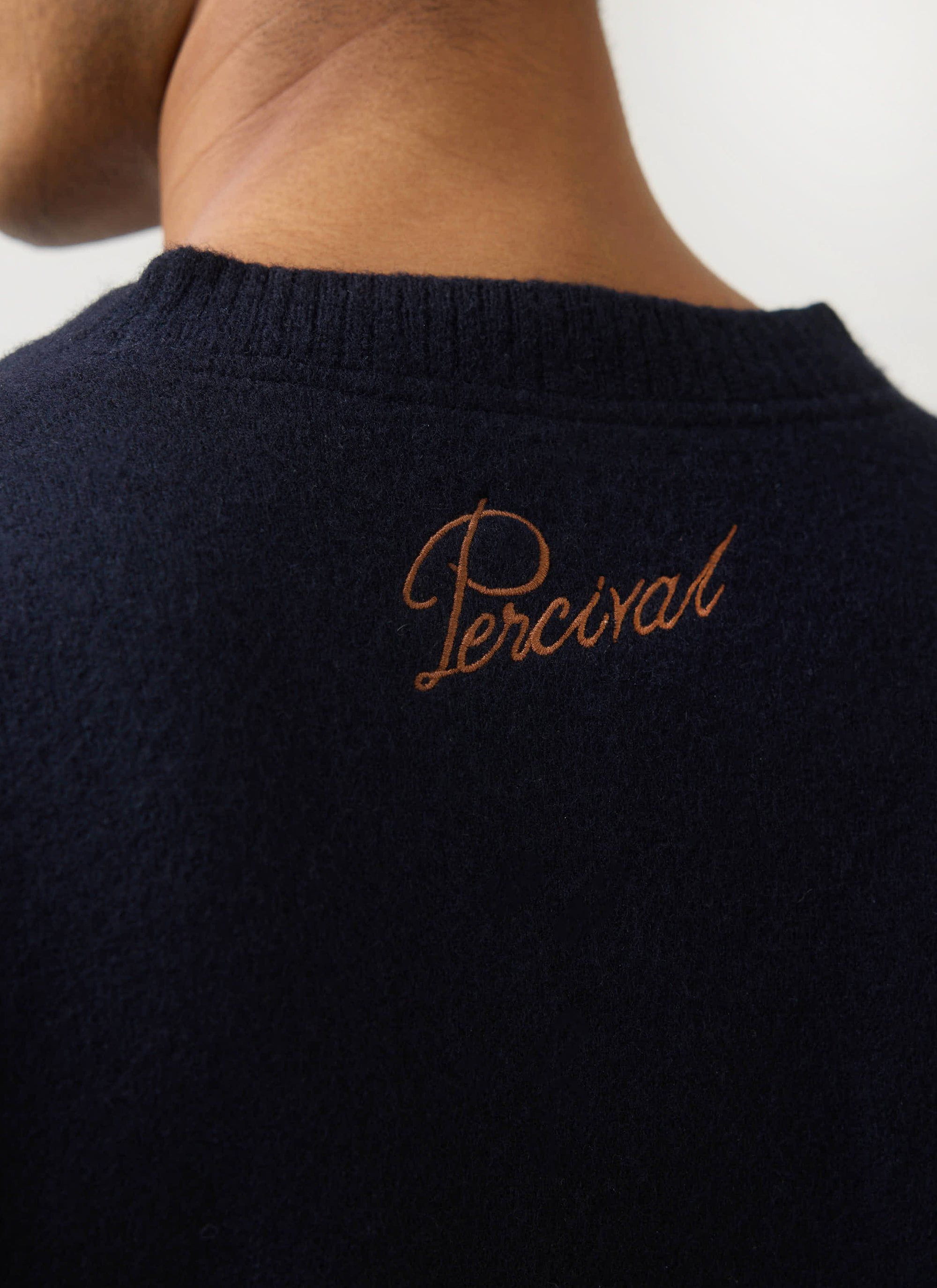 Close-up of the brown Percival script embroidery on the back of the navy merino wool jumper from the Guinness collaboration.