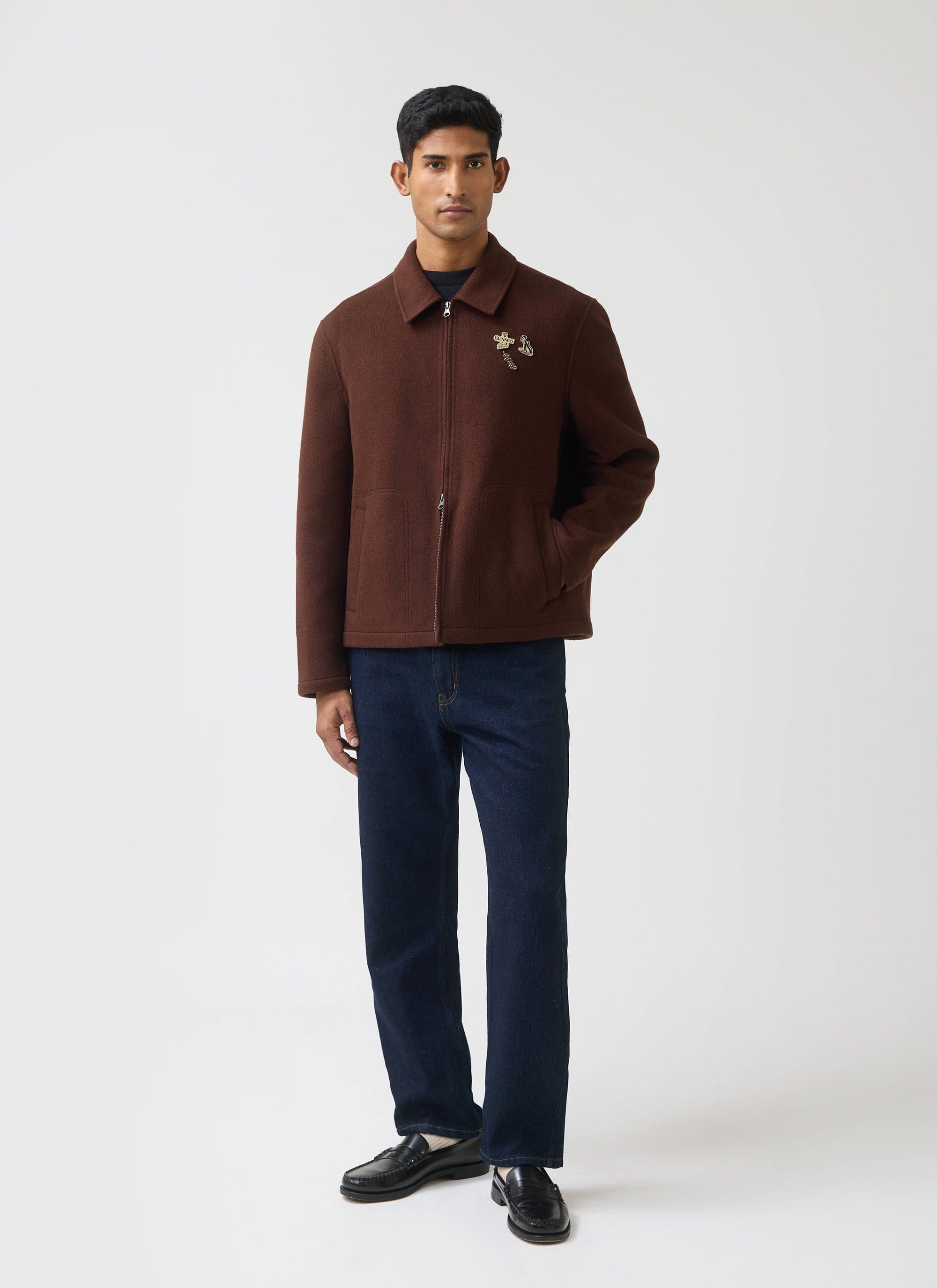 A model wears the Guinness x Percival Wool Jacket in espresso, styled with dark jeans and loafers against a white background.