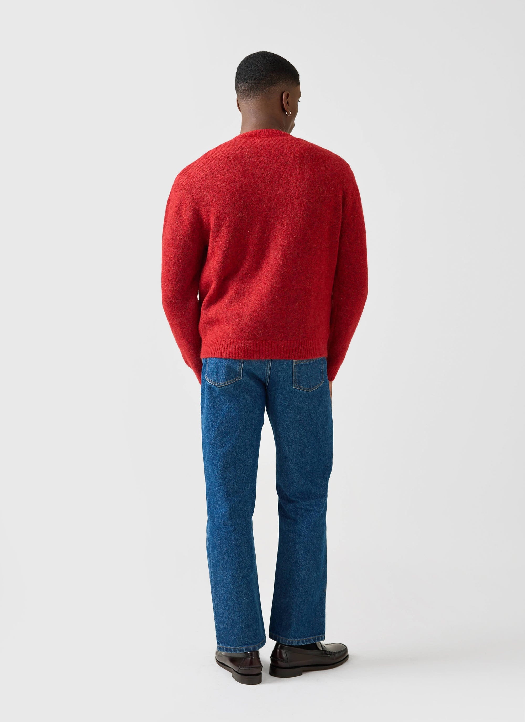 A man models the red White Glove Knitted Cardigan from the Percival x Champion collection, shot from behind.