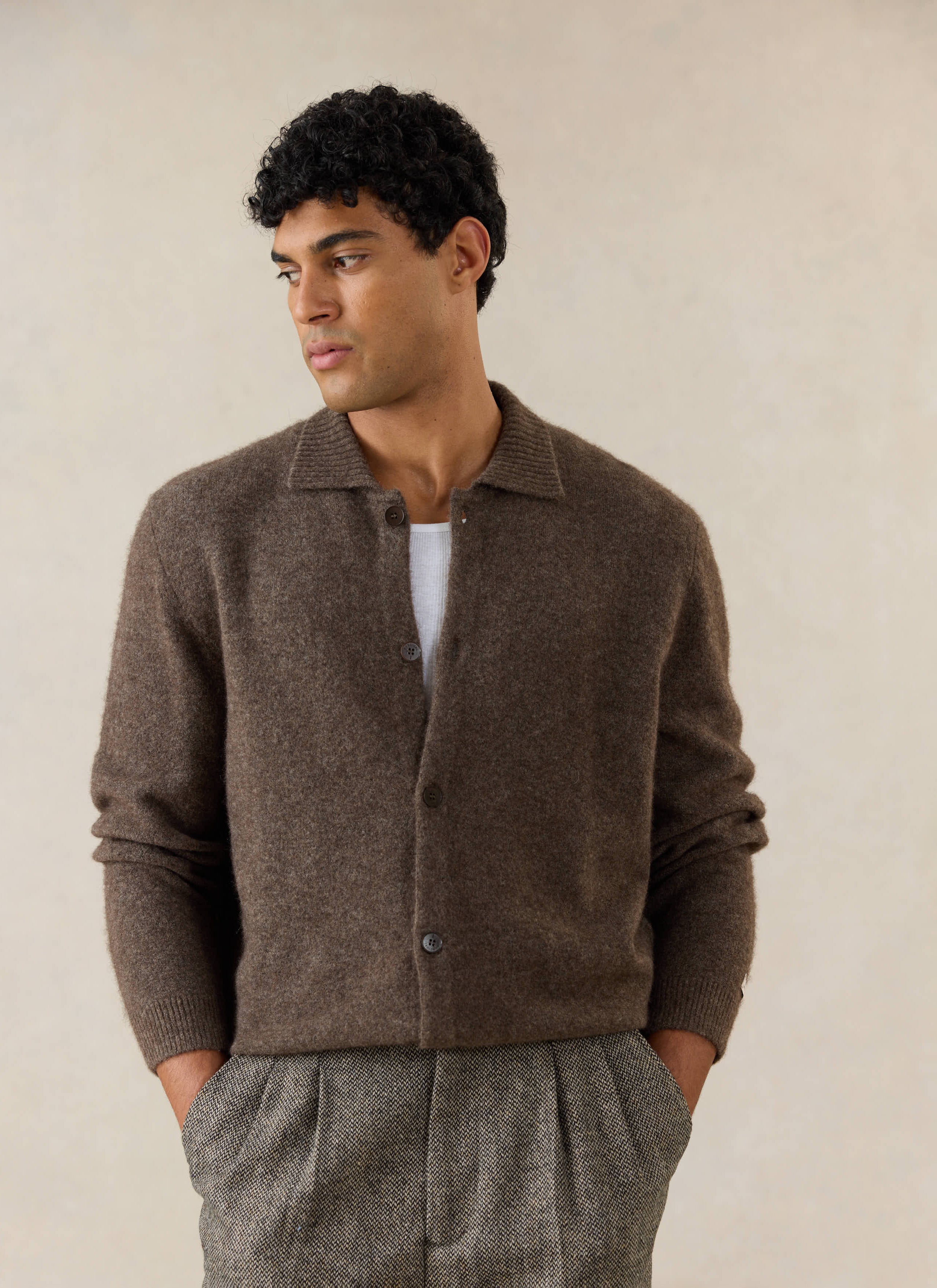 A model wears the brown Archive Knit Collared Cardigan from Percival in yak wool, styled with textured trousers.