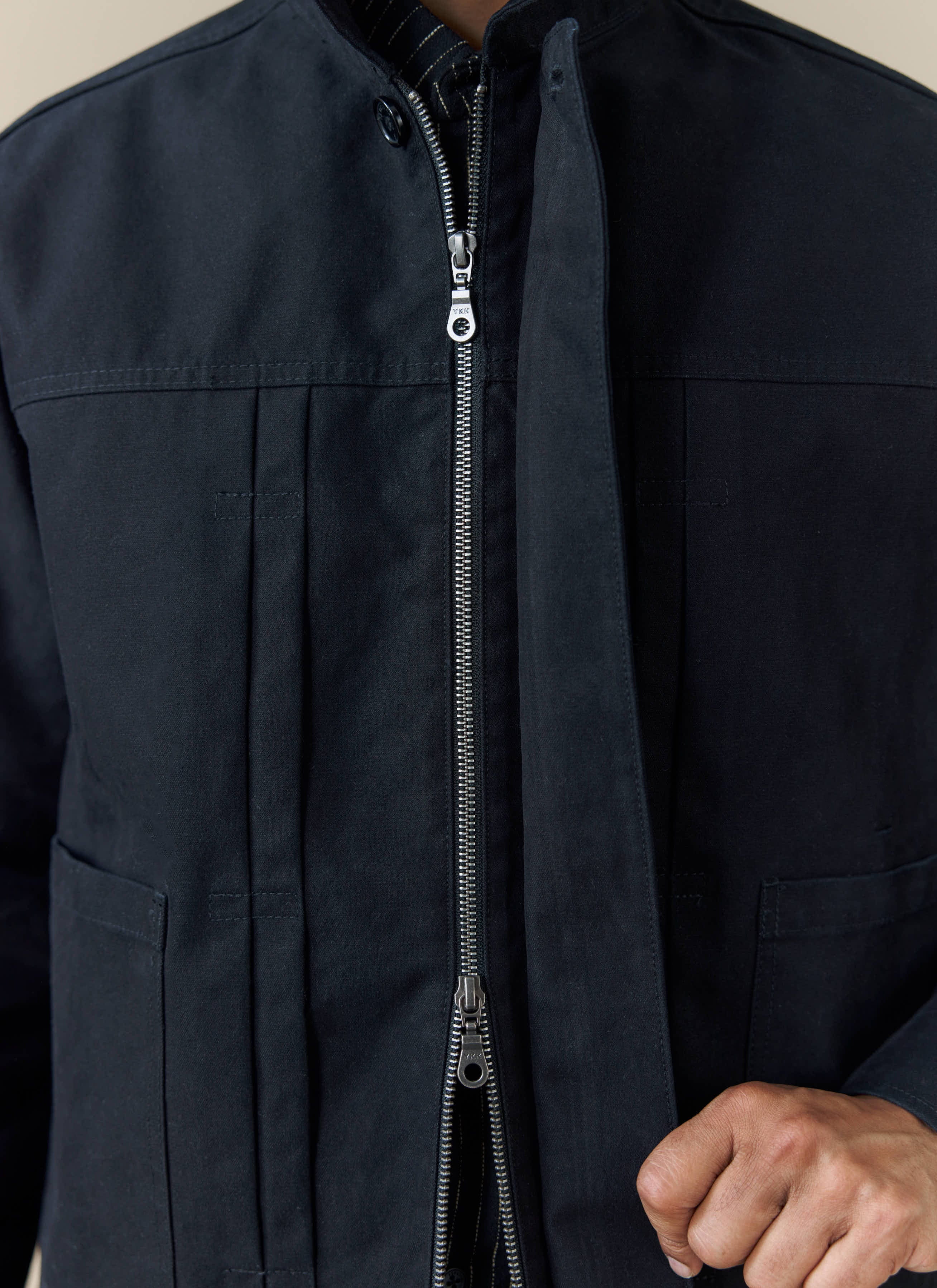 A close-up of the black Ernst Jacket from Percival, showing the double zip and pleated front detailing.