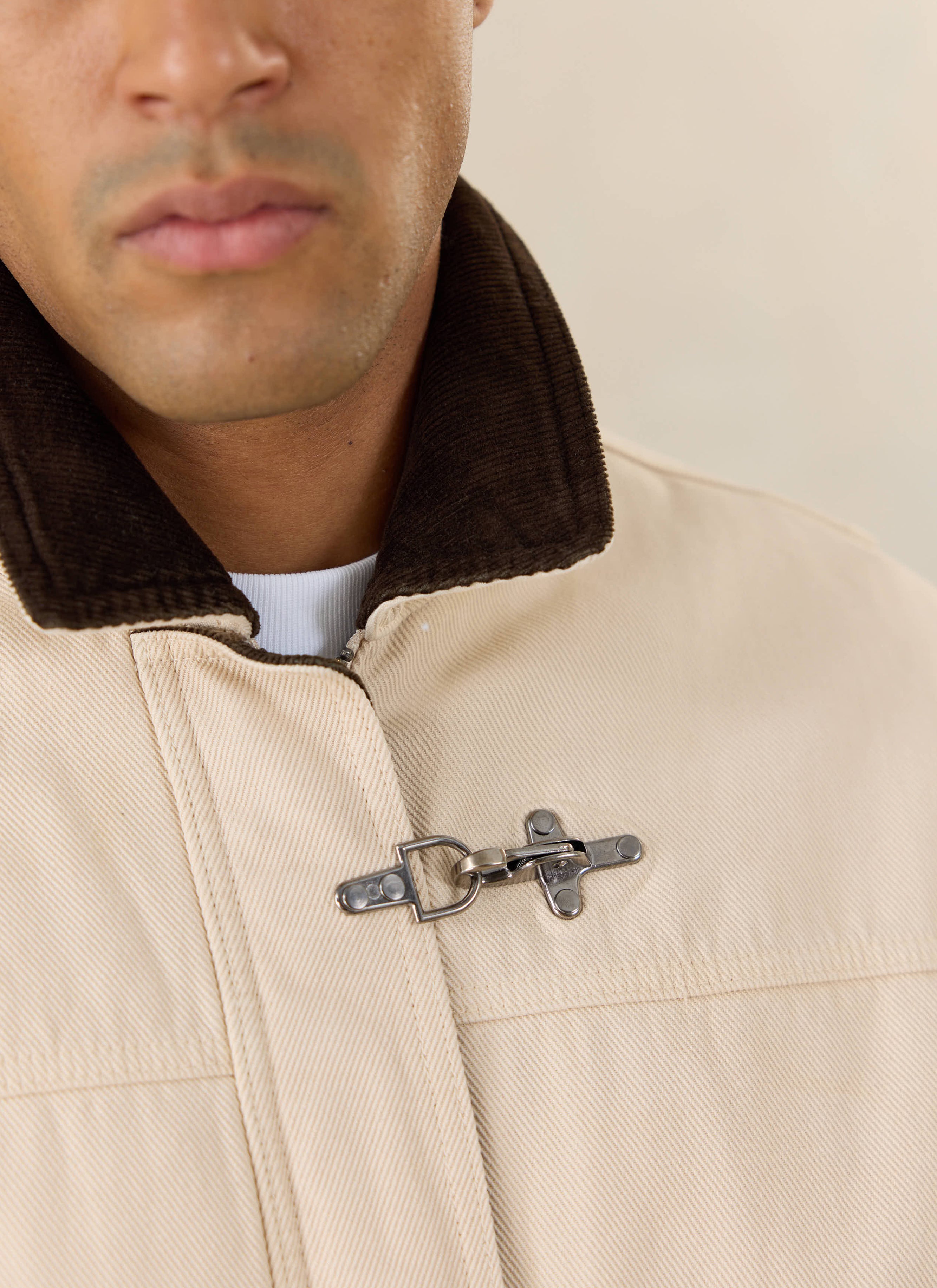 Close-up of a model wearing the cream Percival Fontane jacket, highlighting the brown corduroy collar and metal clasp detail.