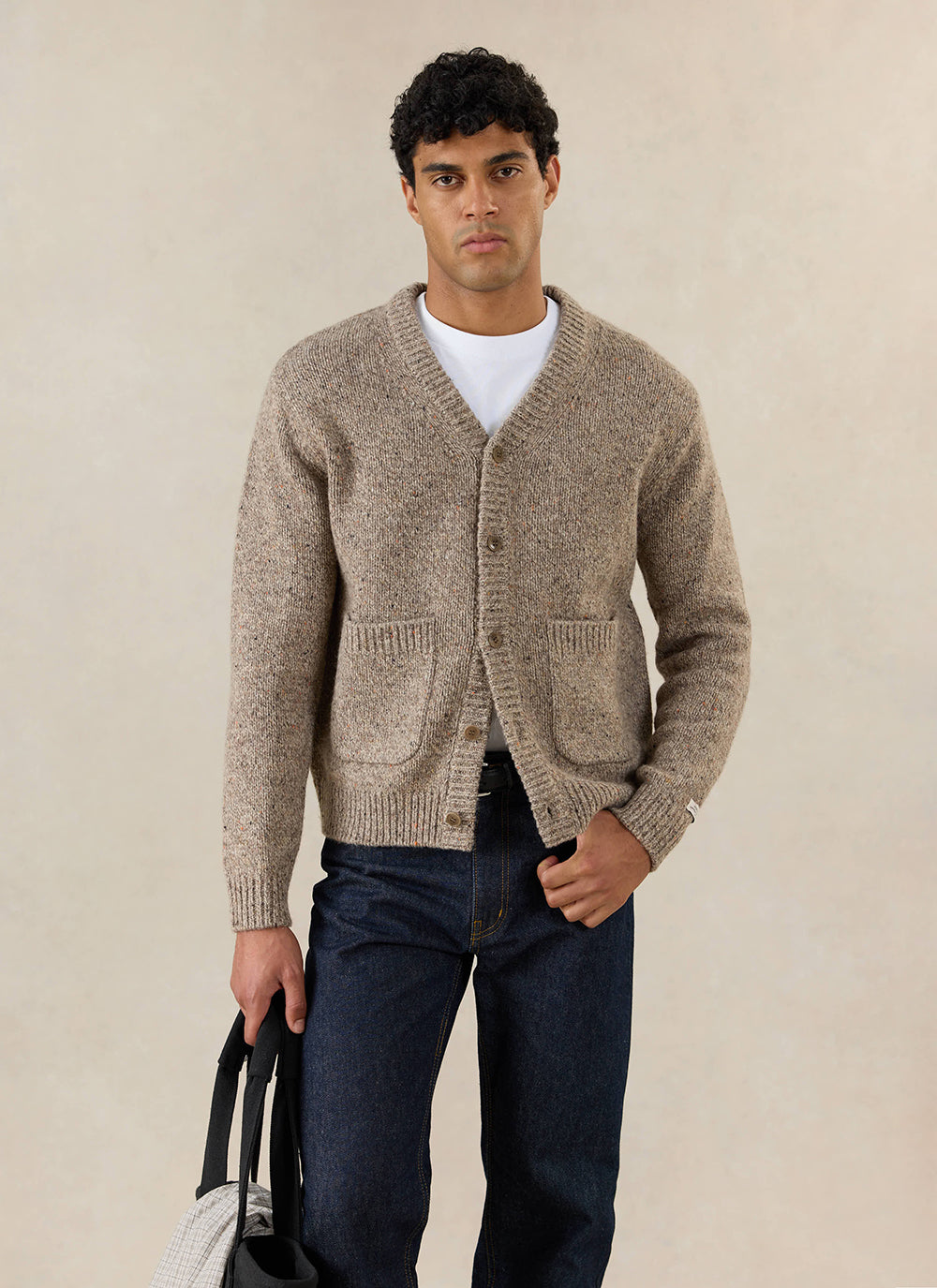 A model wears the oak Percival Rhodes cardigan over a white tee and dark jeans.