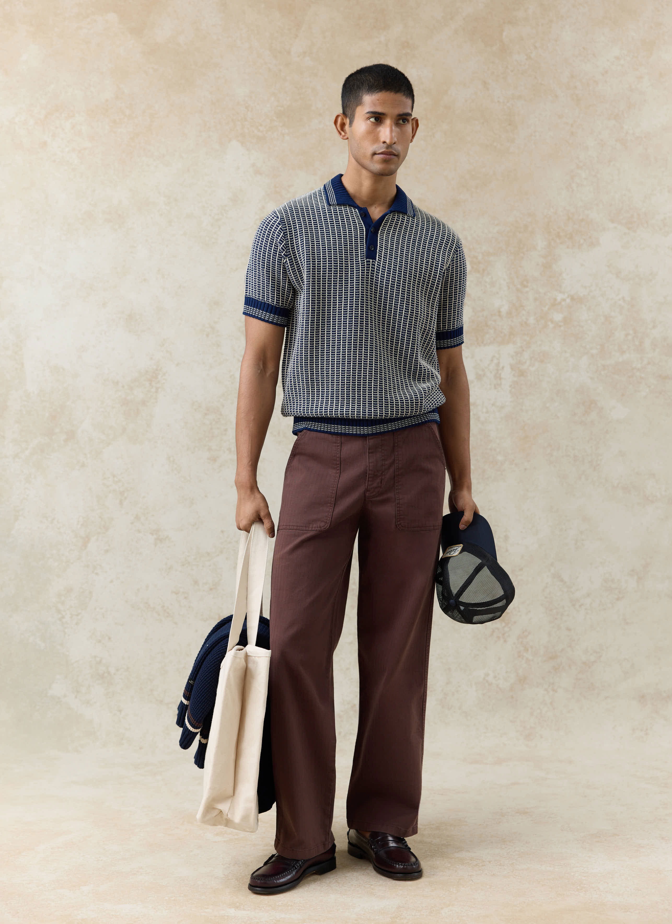 Percival navy Claude knitted polo in a two-tone textured cotton, styled with brown trousers and dark loafers.