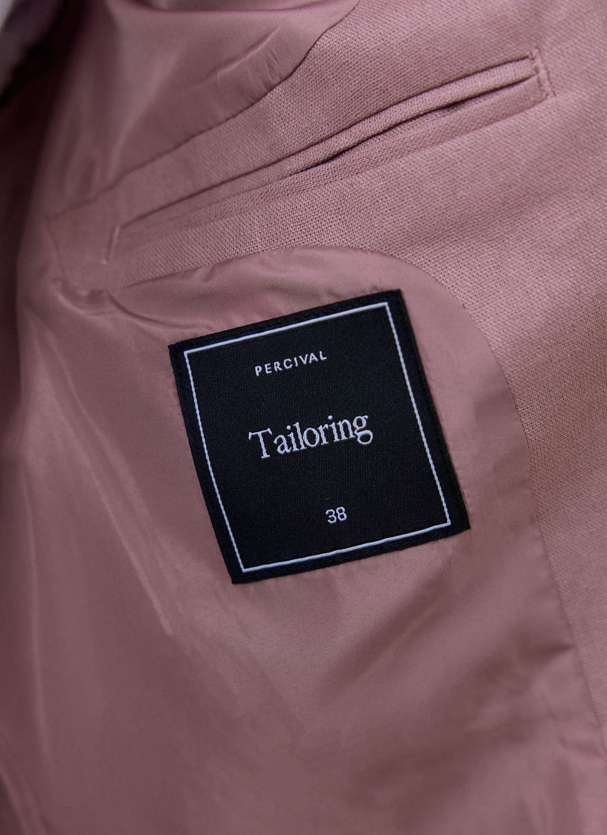 Internal black 'Tailoring' label and size tag on the dusty pink lining of the Percival linen blazer.