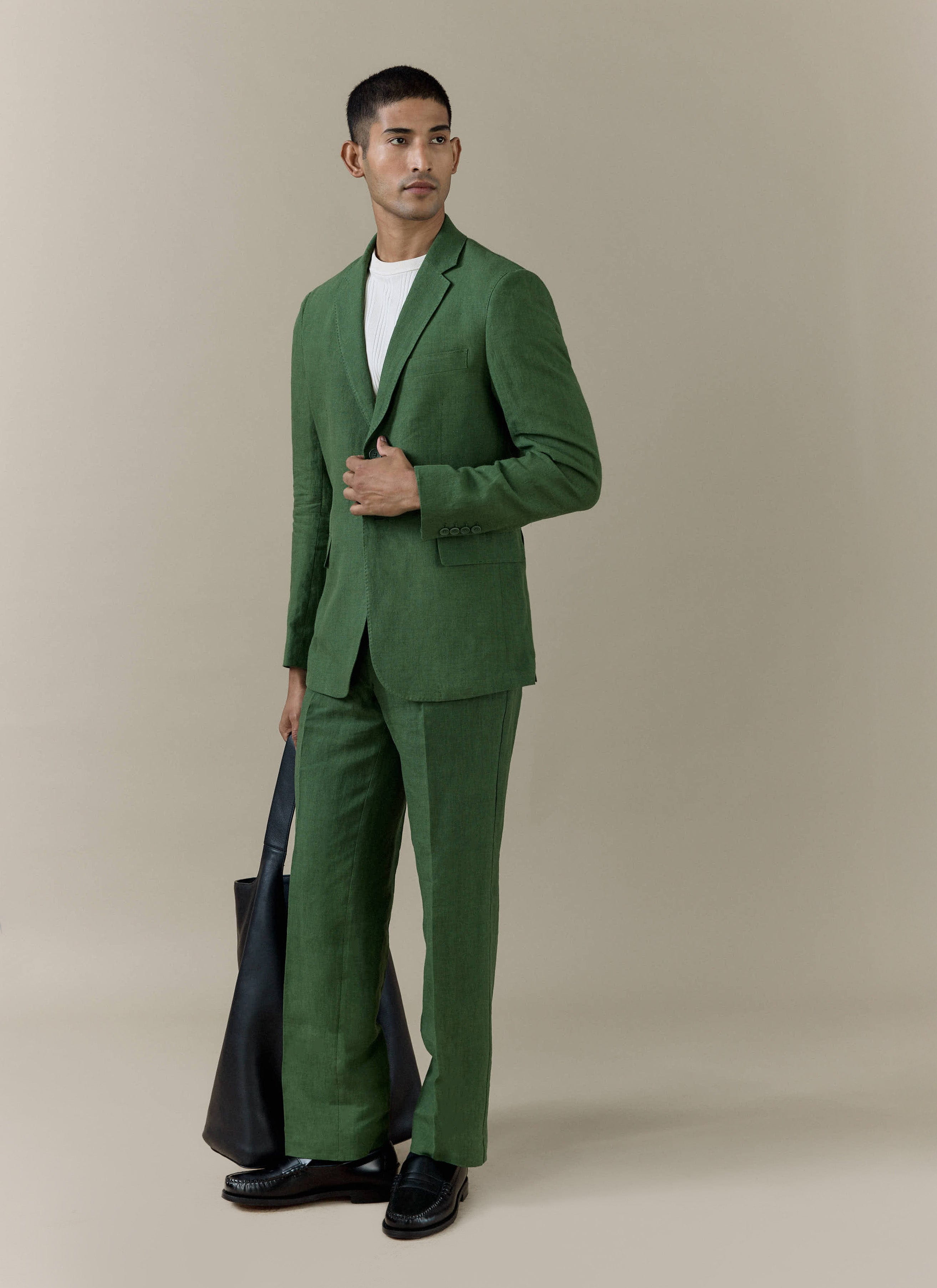 Forest green Percival slim fit classic blazer in 100% linen, styled with matching trousers and a black leather tote bag.