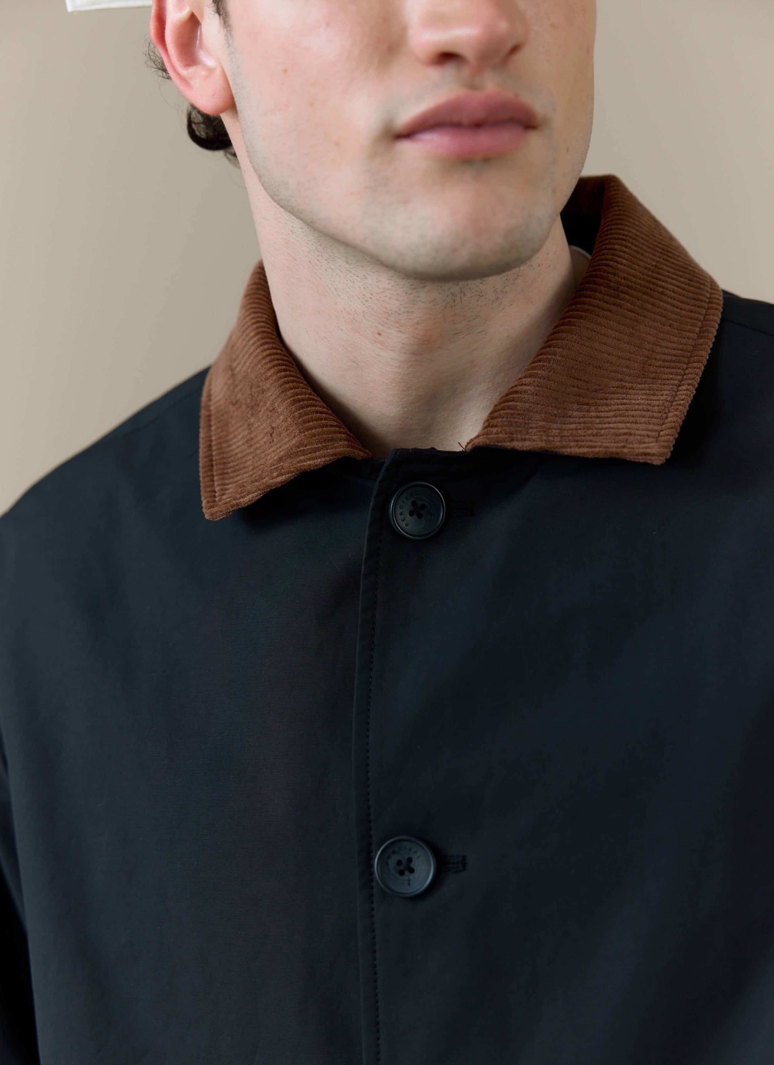 Close-up of the brown corduroy collar and top buttons on the Percival Cord Collar Relaxed Trench Coat in black.