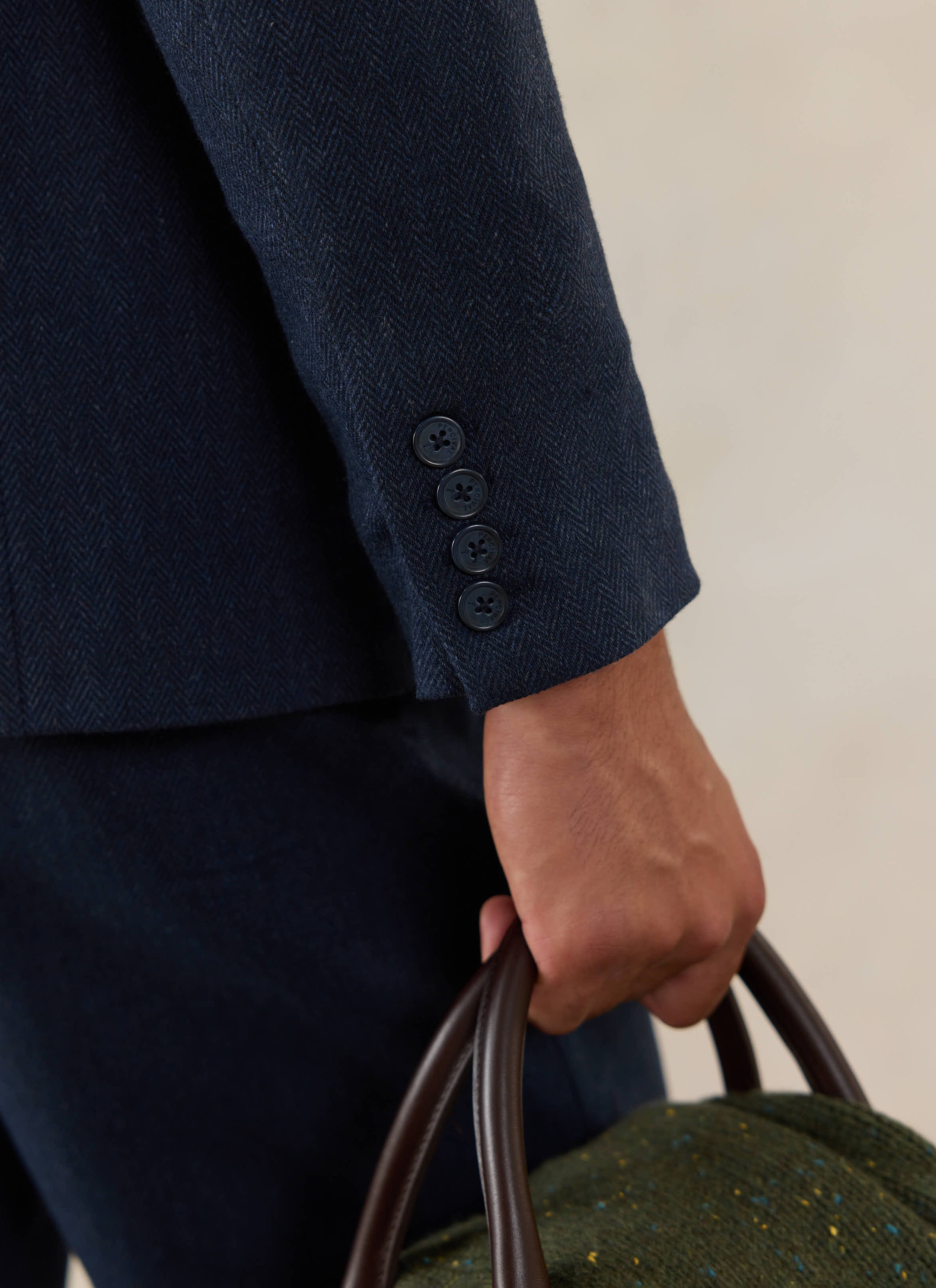 A close-up of the Percival Tailored Blazer in Navy Herringbone Wool, showing the branded four-button cuff.