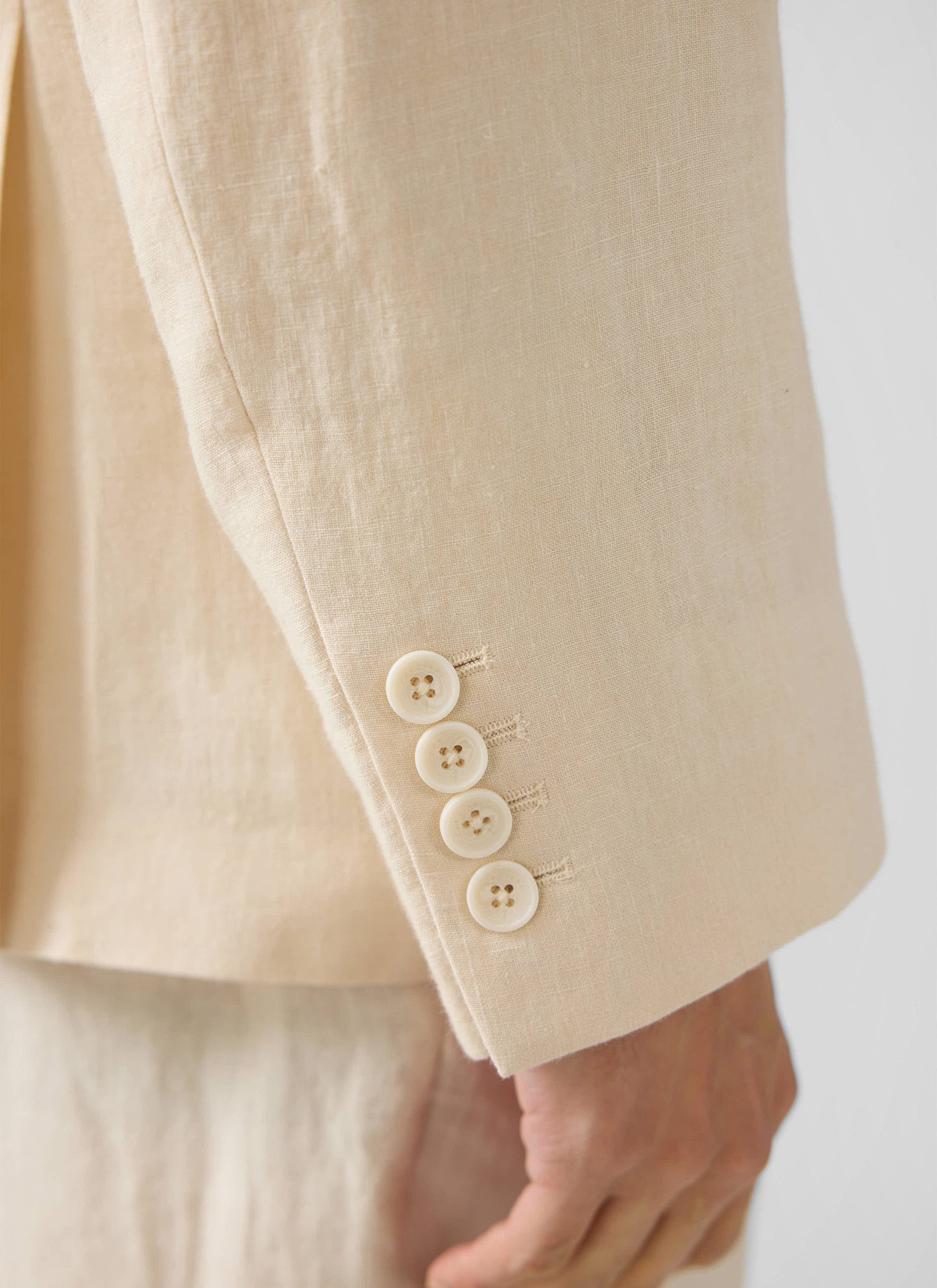 Close-up of the Clifton Double Breasted Blazer from Percival, showing the four-button cuff detail on the cream linen fabric.