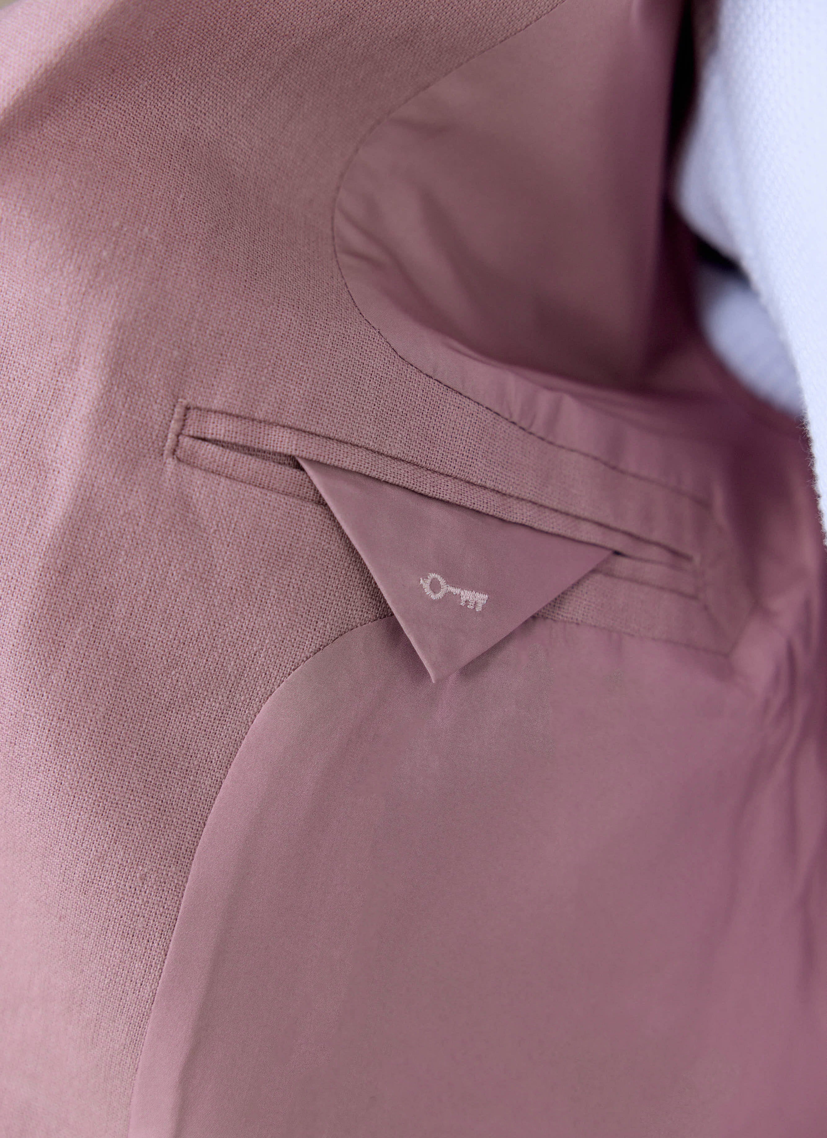Internal pocket detail on the dusty pink Percival tailored linen blazer, featuring a small embroidered key motif.