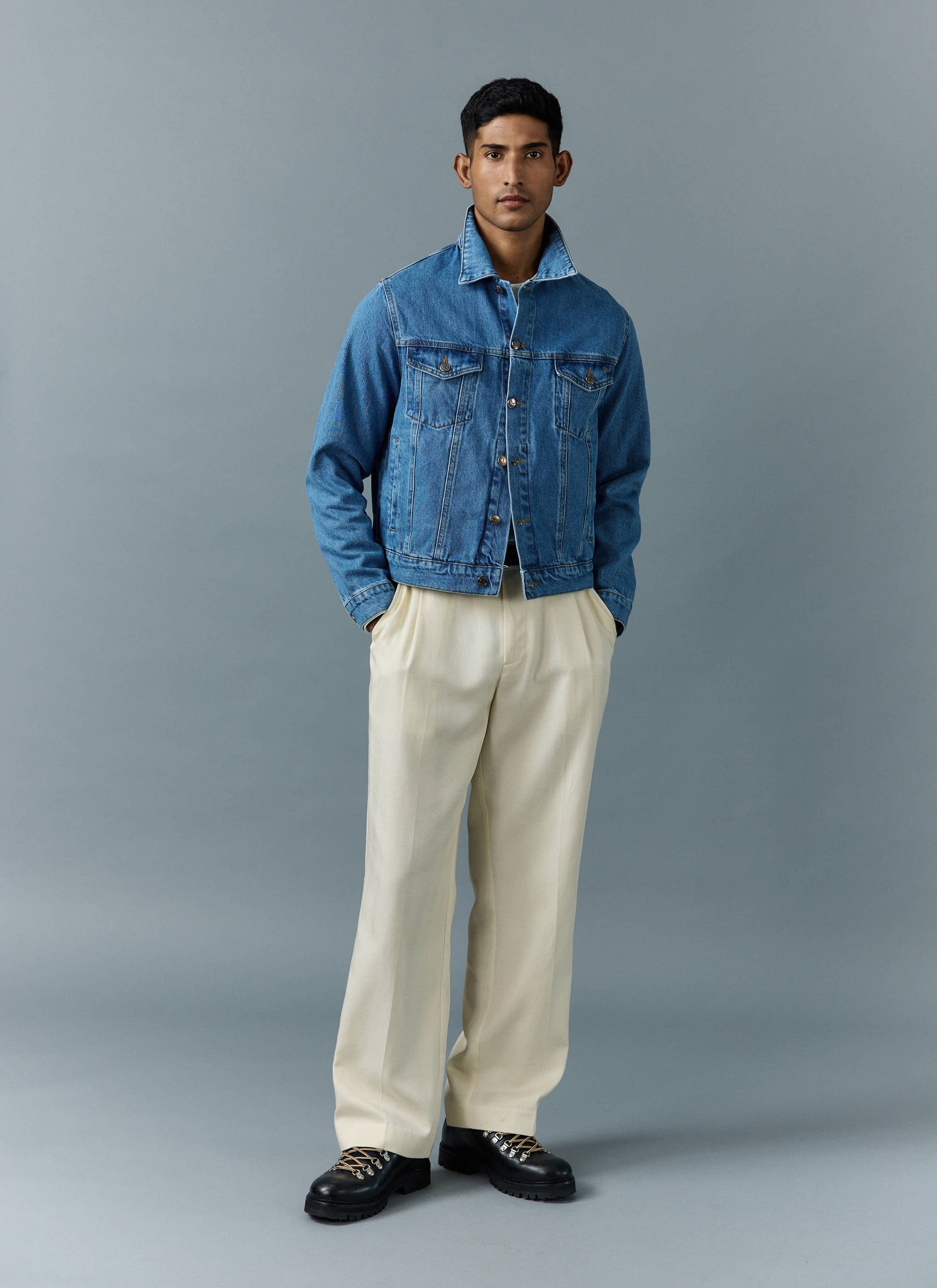A model wears the Percival Western Trucker Jacket in light wash blue, styled with cream trousers and chunky black boots.