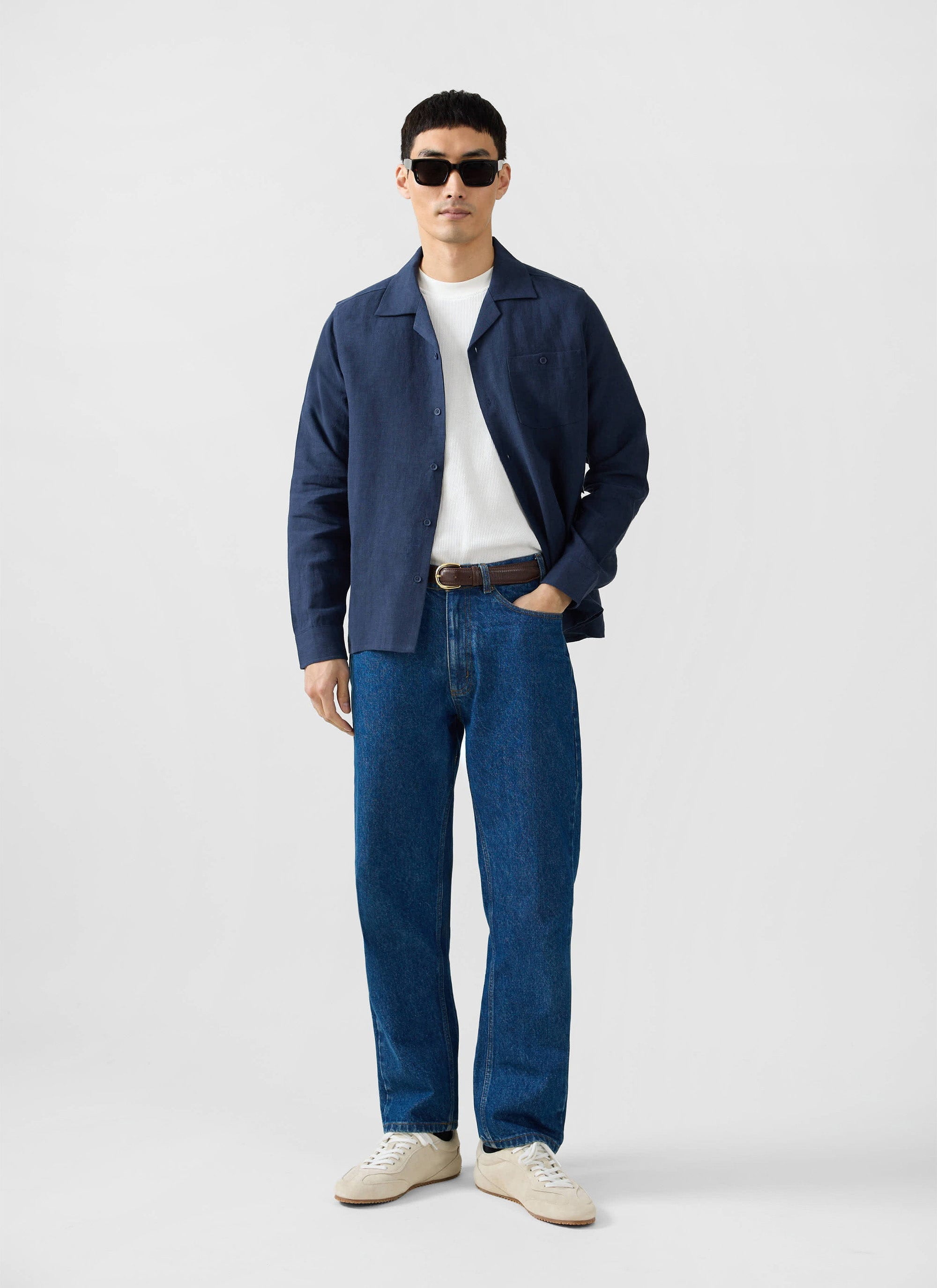 A model wears the Percival Long Sleeve Cuban Linen Shirt in navy, styled open over a white t-shirt with blue jeans.