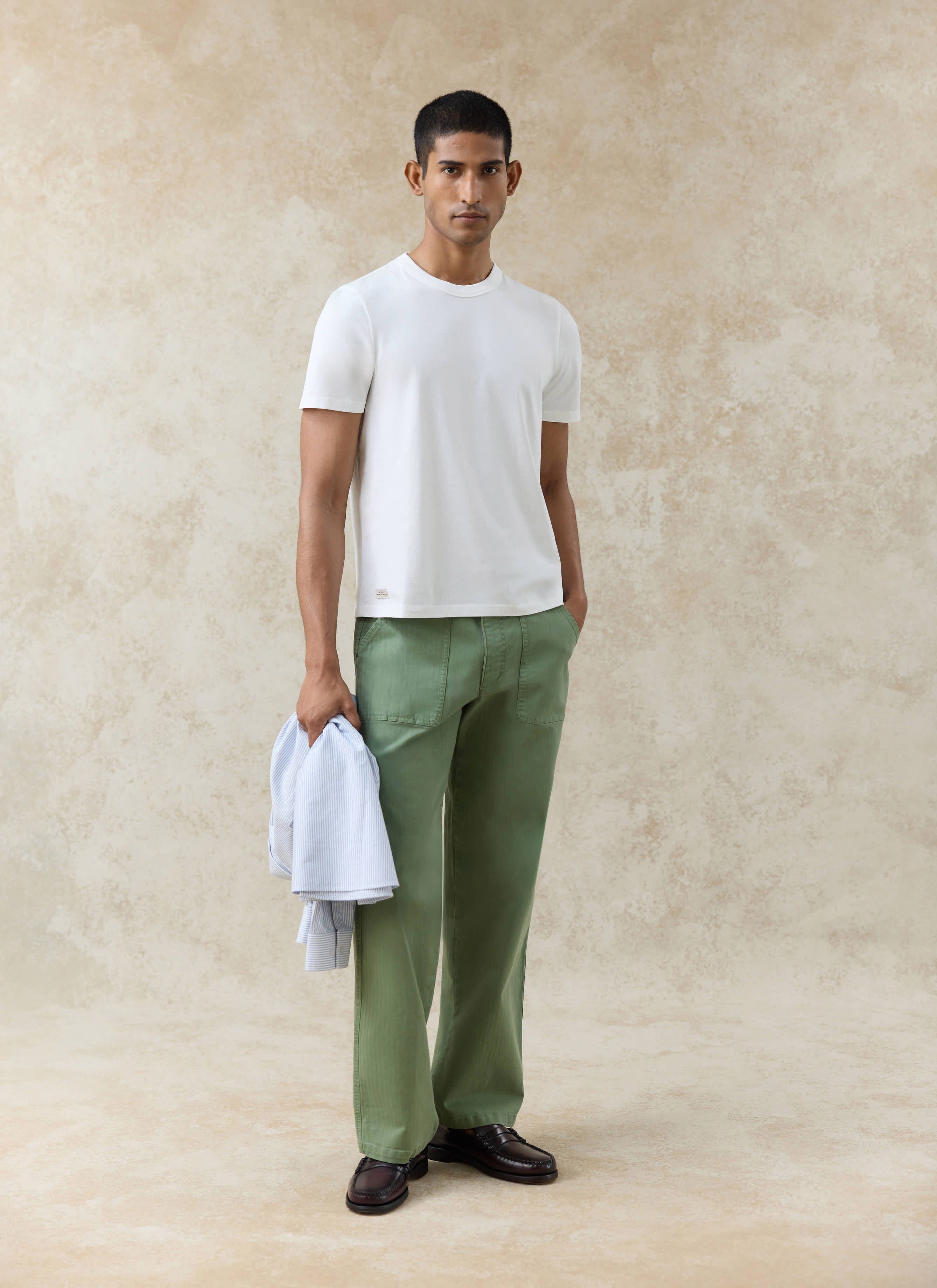 Percival Austin Slub Slim Fit T-shirt in off-white organic cotton, styled with green trousers and a striped shirt.