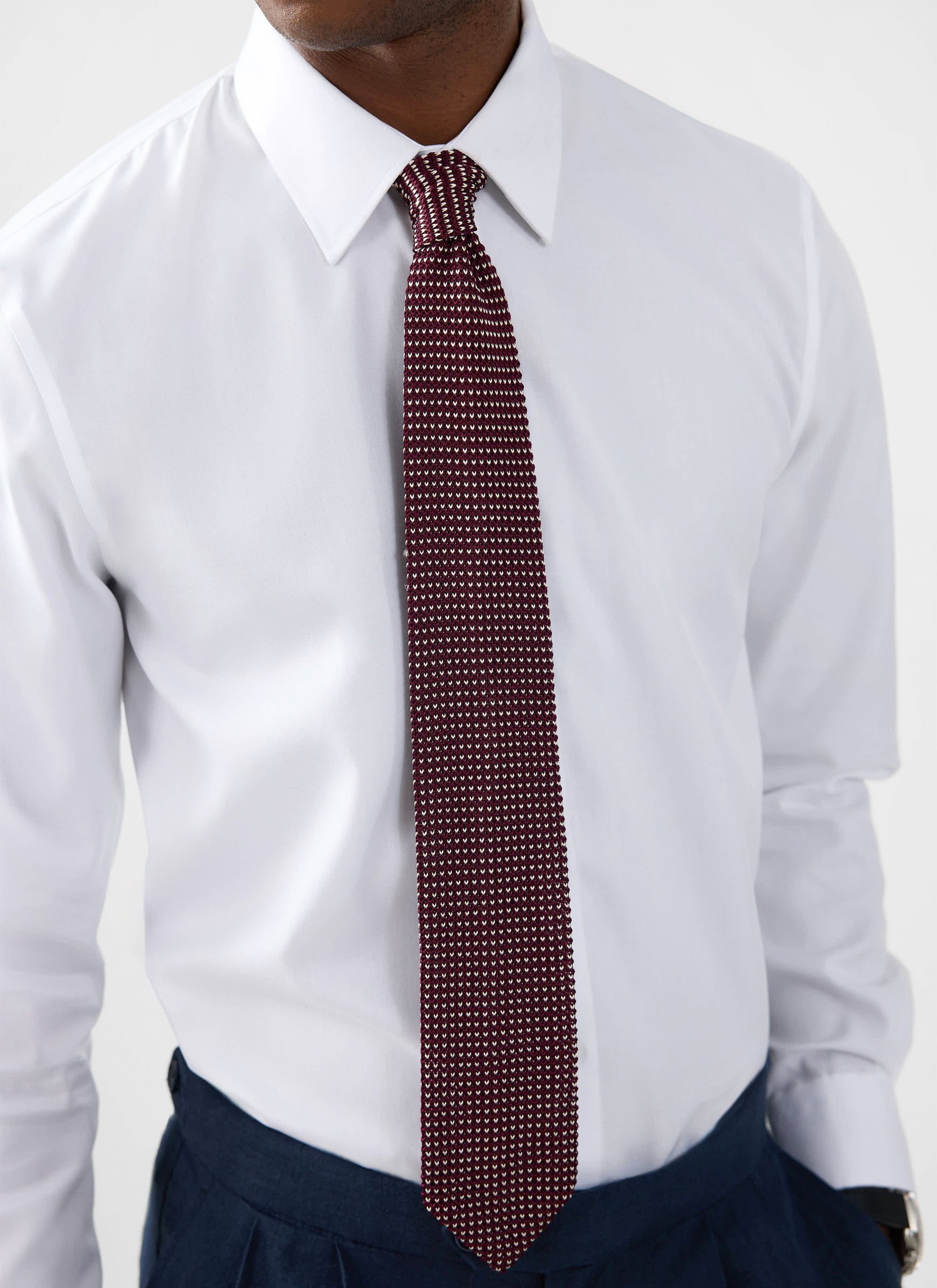 Close-up of a model wearing the white Percival Formal Classic Shirt, styled with a burgundy patterned tie and navy trousers.