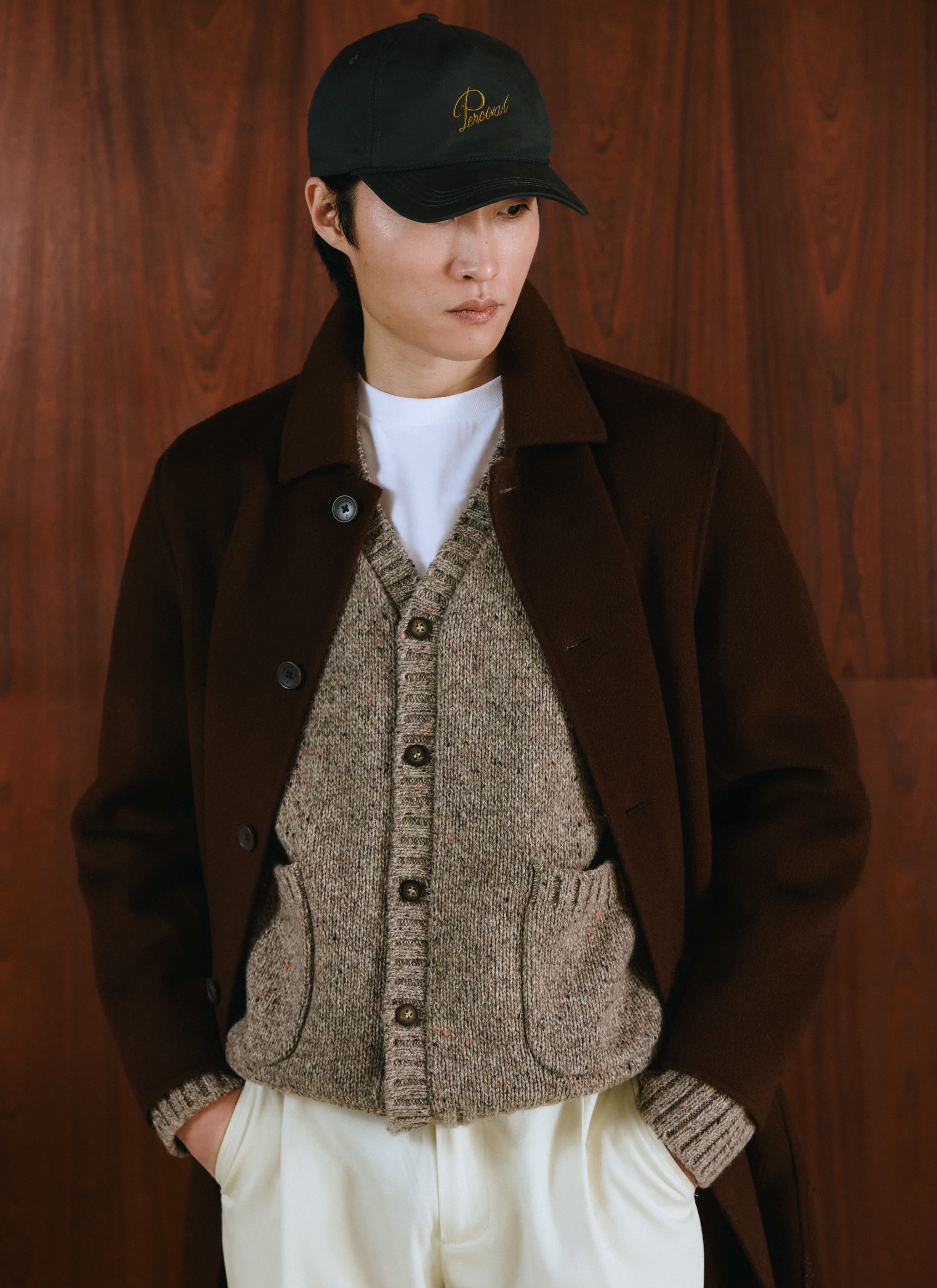 Model wearing the charcoal Percival cap, styled with brown overcoat, knit cardigan, and white tee.