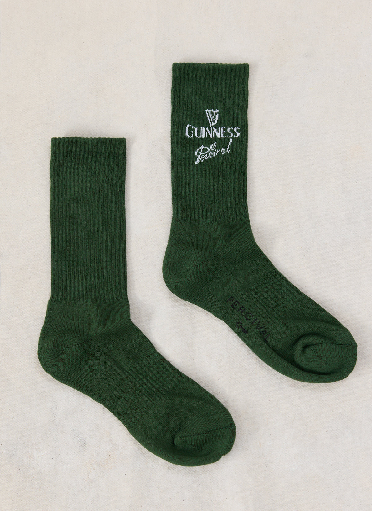 Forest green Guinness x Percival ribbed crew socks featuring knitted white branding on a neutral background.