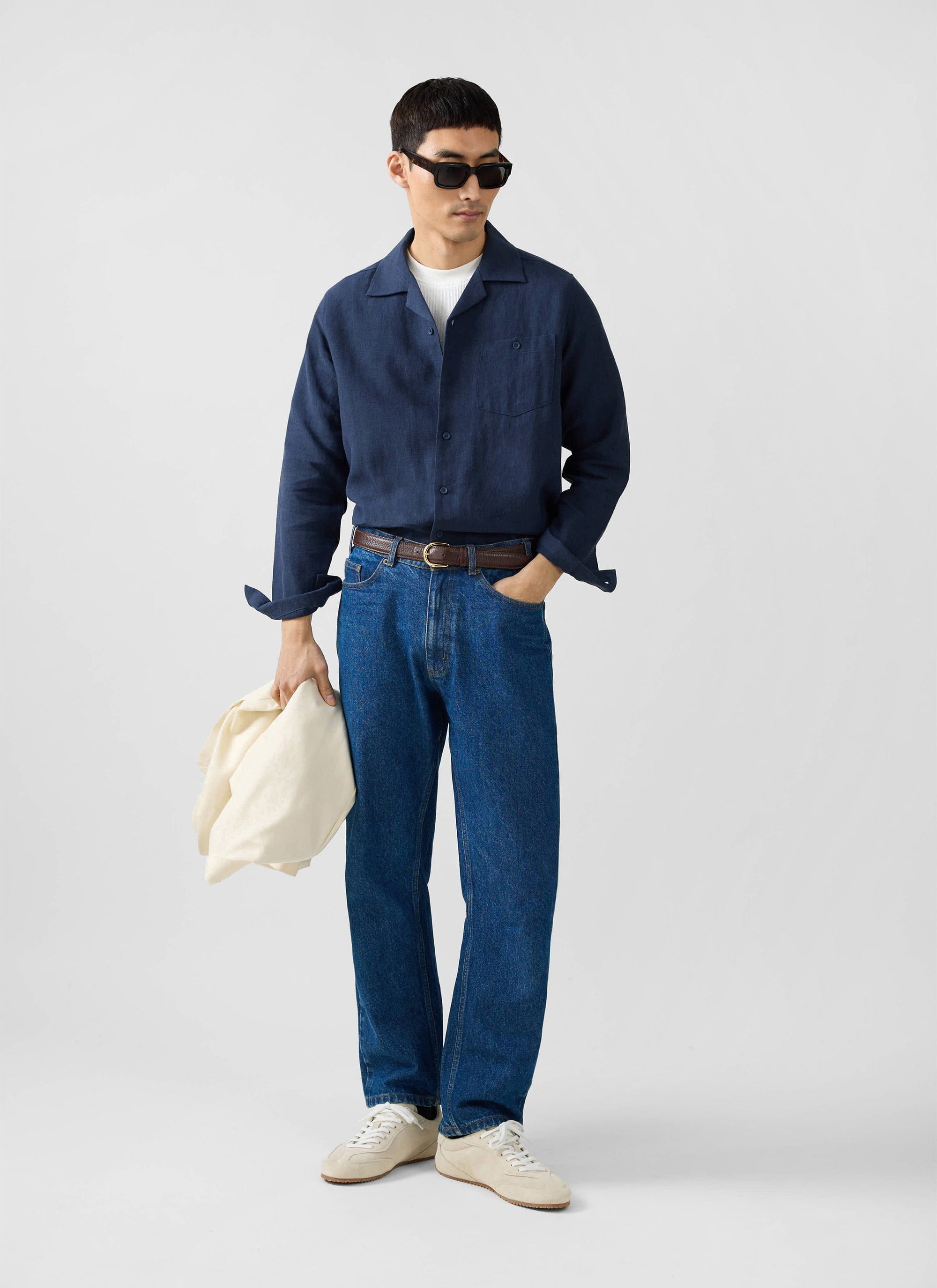 A model wears the Percival Long Sleeve Cuban Linen Shirt in navy, styled with jeans, a white tee, and sunglasses.