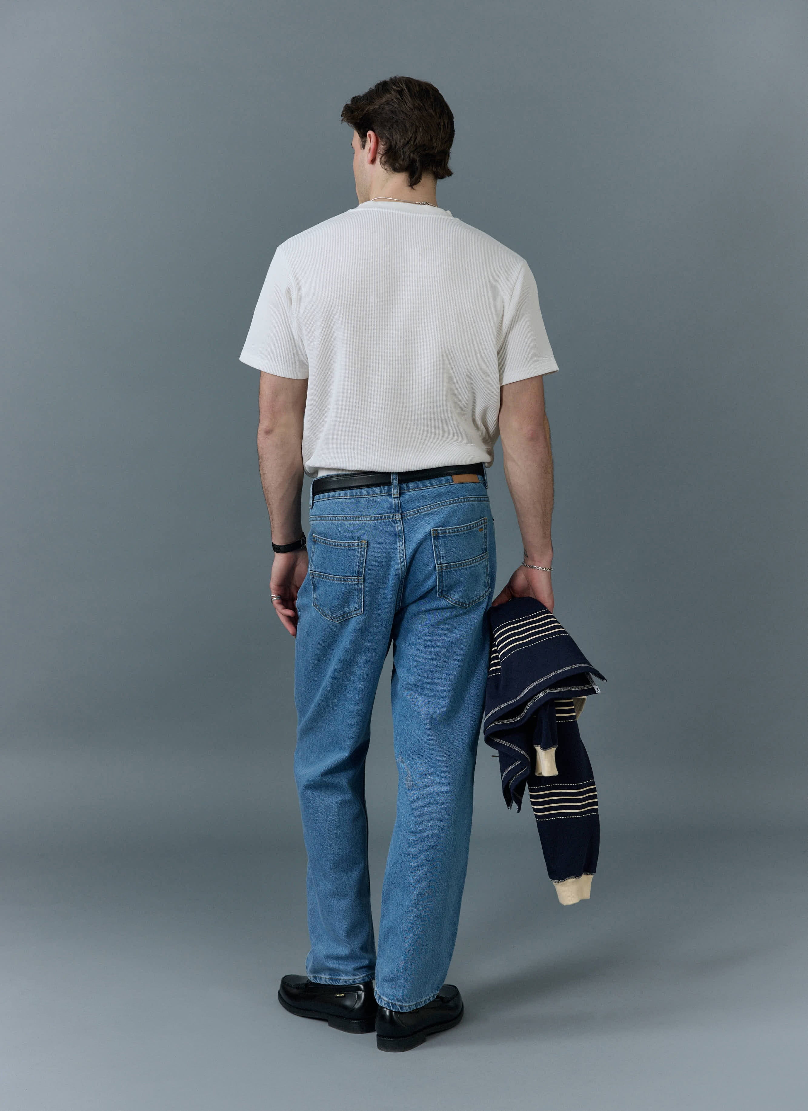 Back view of a model in Percival light wash blue straight leg jeans, paired with a white t-shirt.