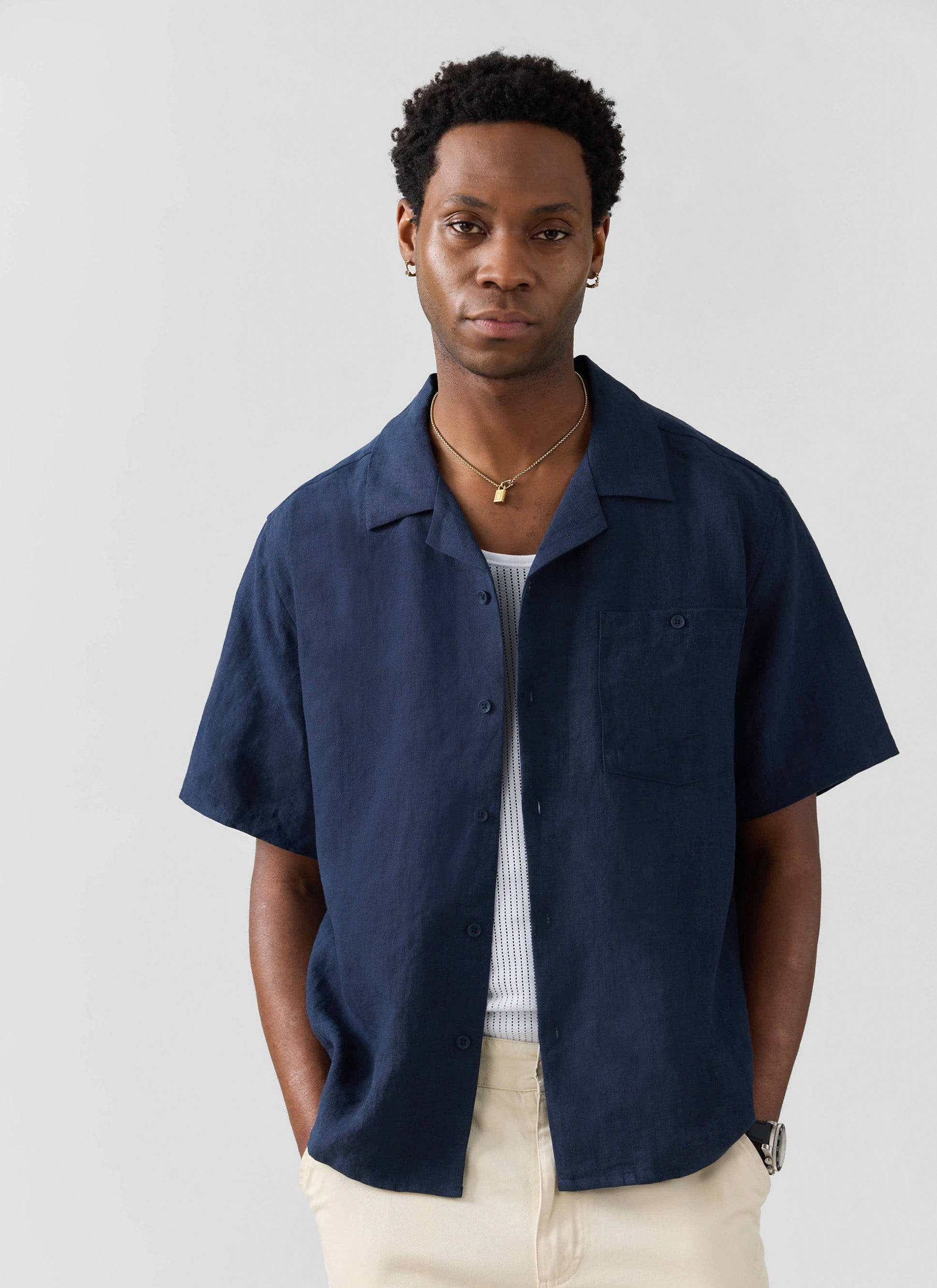 A model wears the Percival navy linen Short Sleeve Cuban Shirt with cream trousers and a white vest.