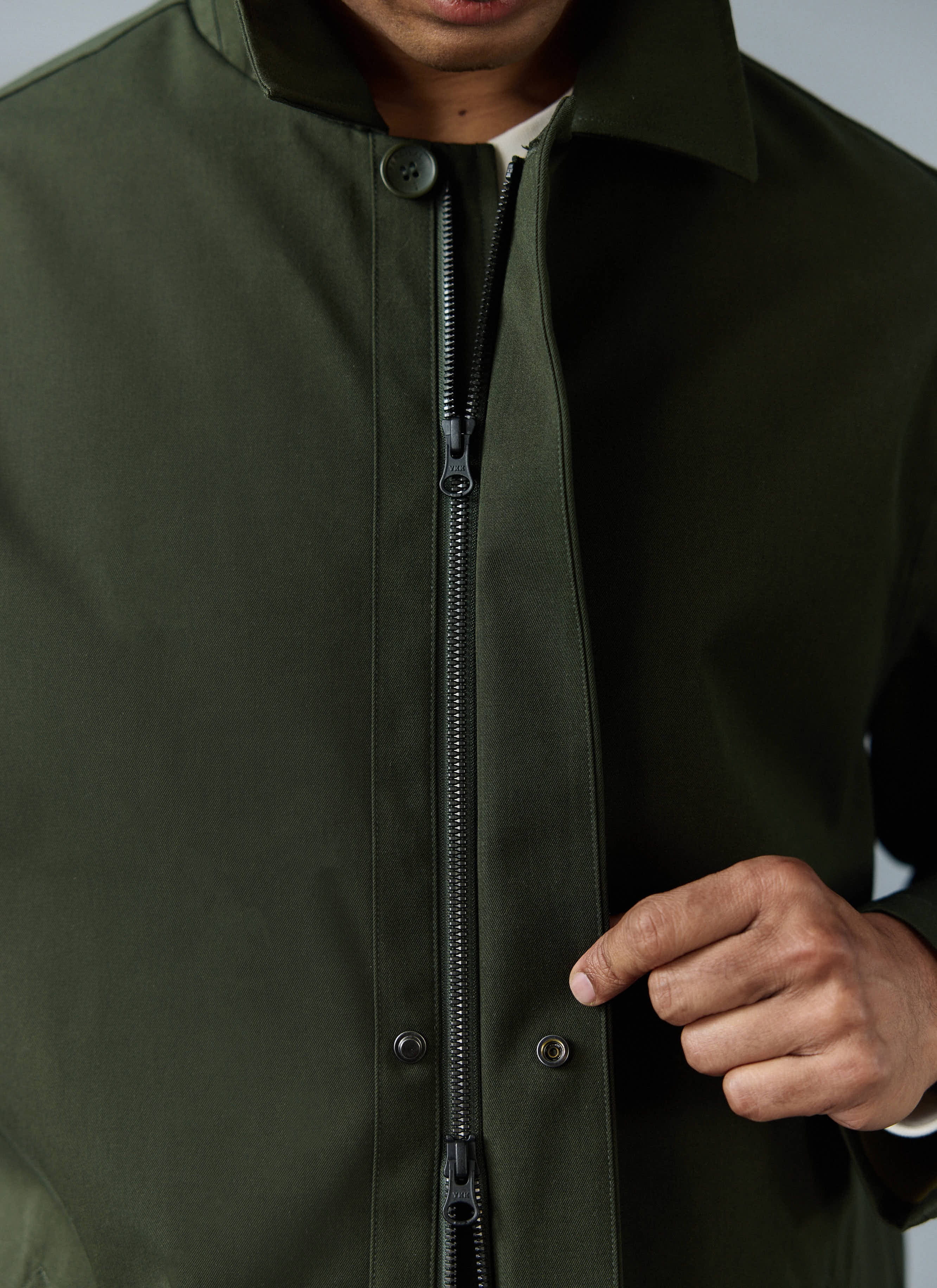 A close-up of the waterproof Greyson Trench Coat in forest green from Percival, showing the zip and snap button fastening.