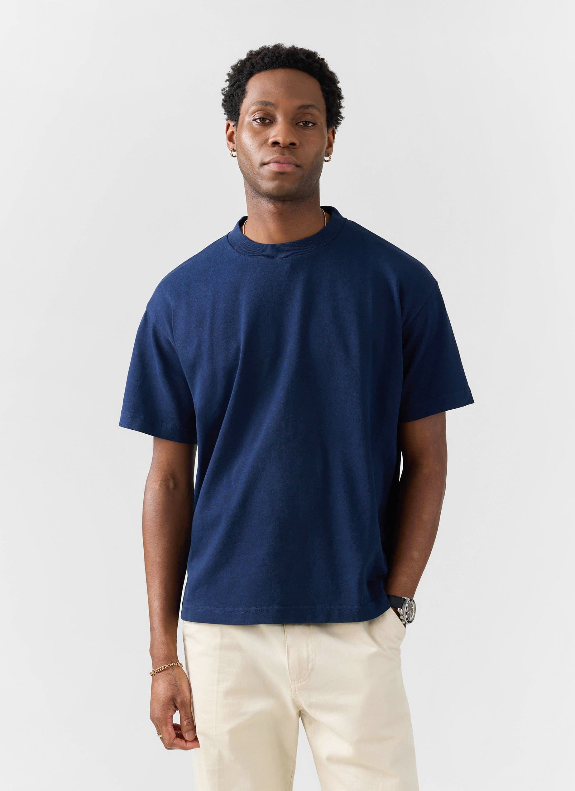 A model wears a navy oversized organic cotton t-shirt from Percival, paired with cream trousers.