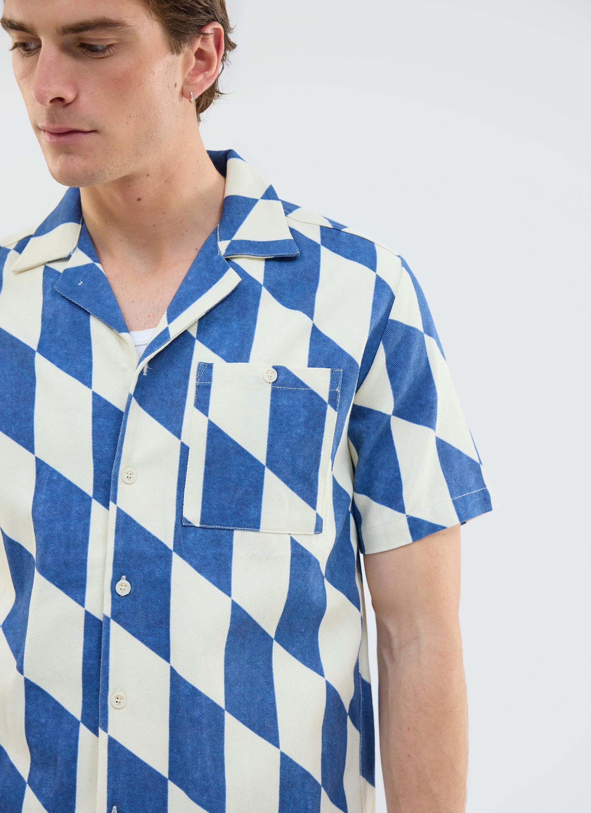 Close up of a model wearing the Percival Market Diamond Cuban Shirt in ecru and navy.