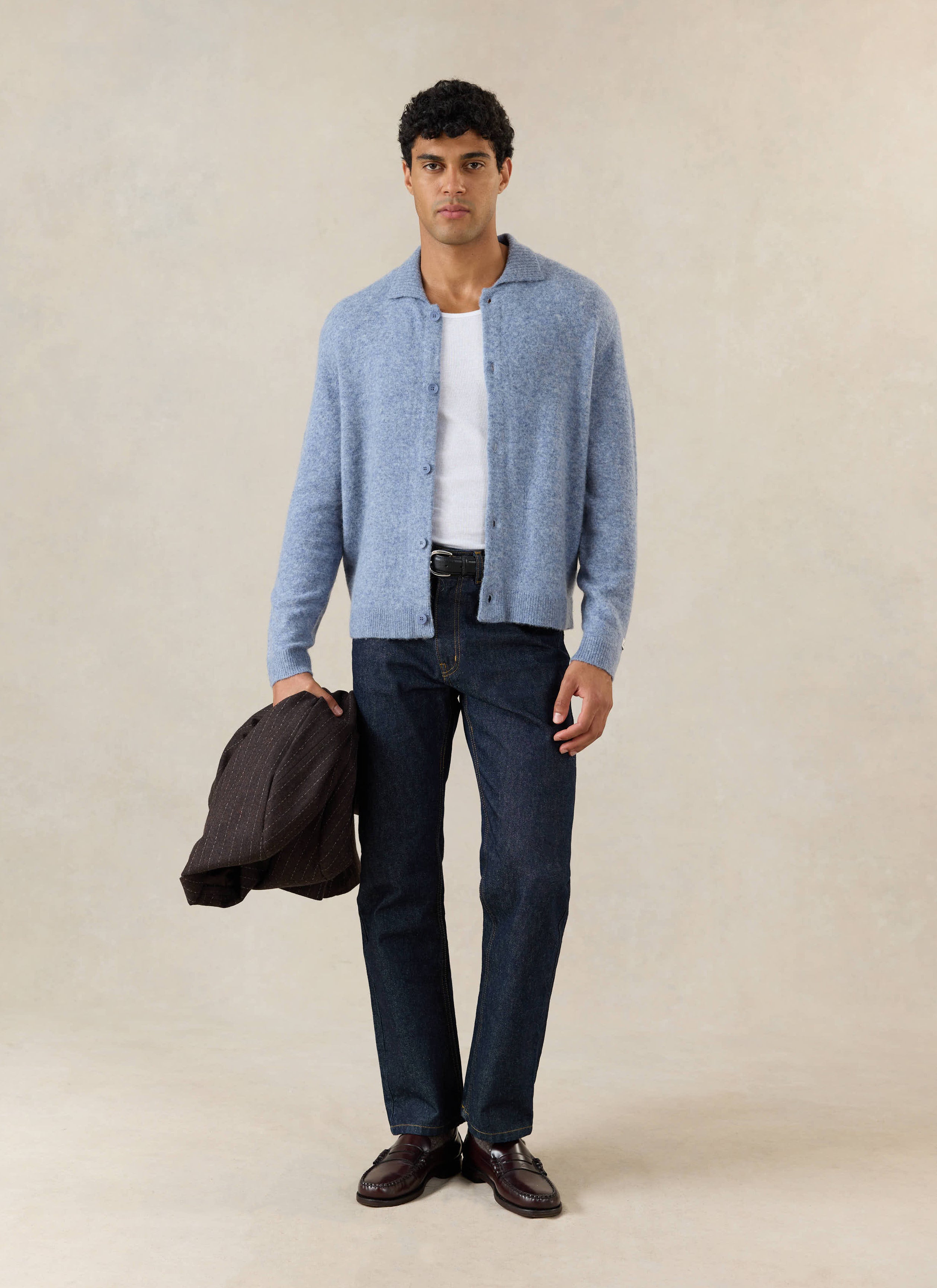 A model wears the Percival heather blue yak wool cardigan, styled over a white tank top with dark jeans and loafers.