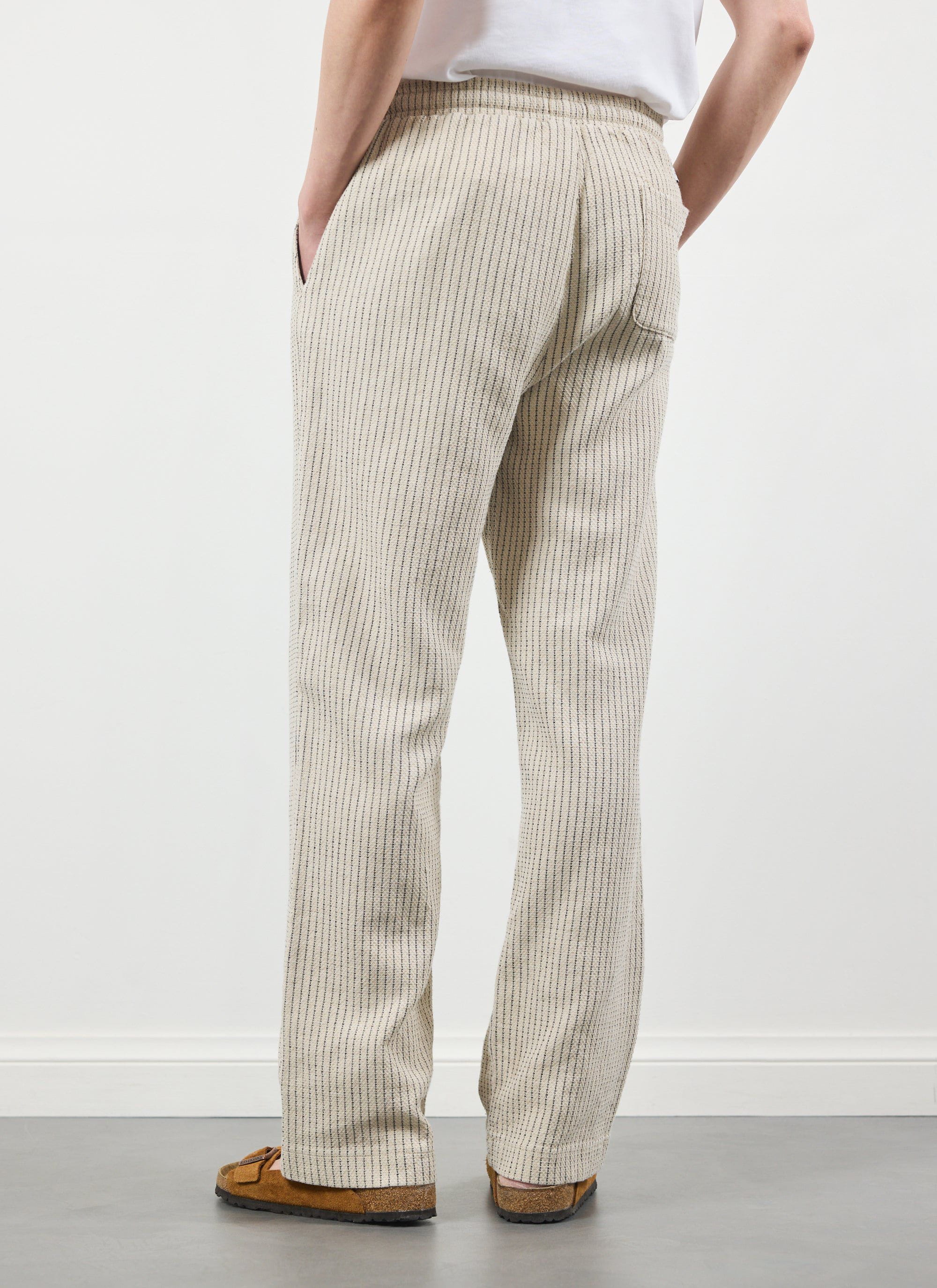 A back view of a model in the Percival Sorrento Linen Trousers in ecru, showing off the relaxed, straight-leg silhouette.