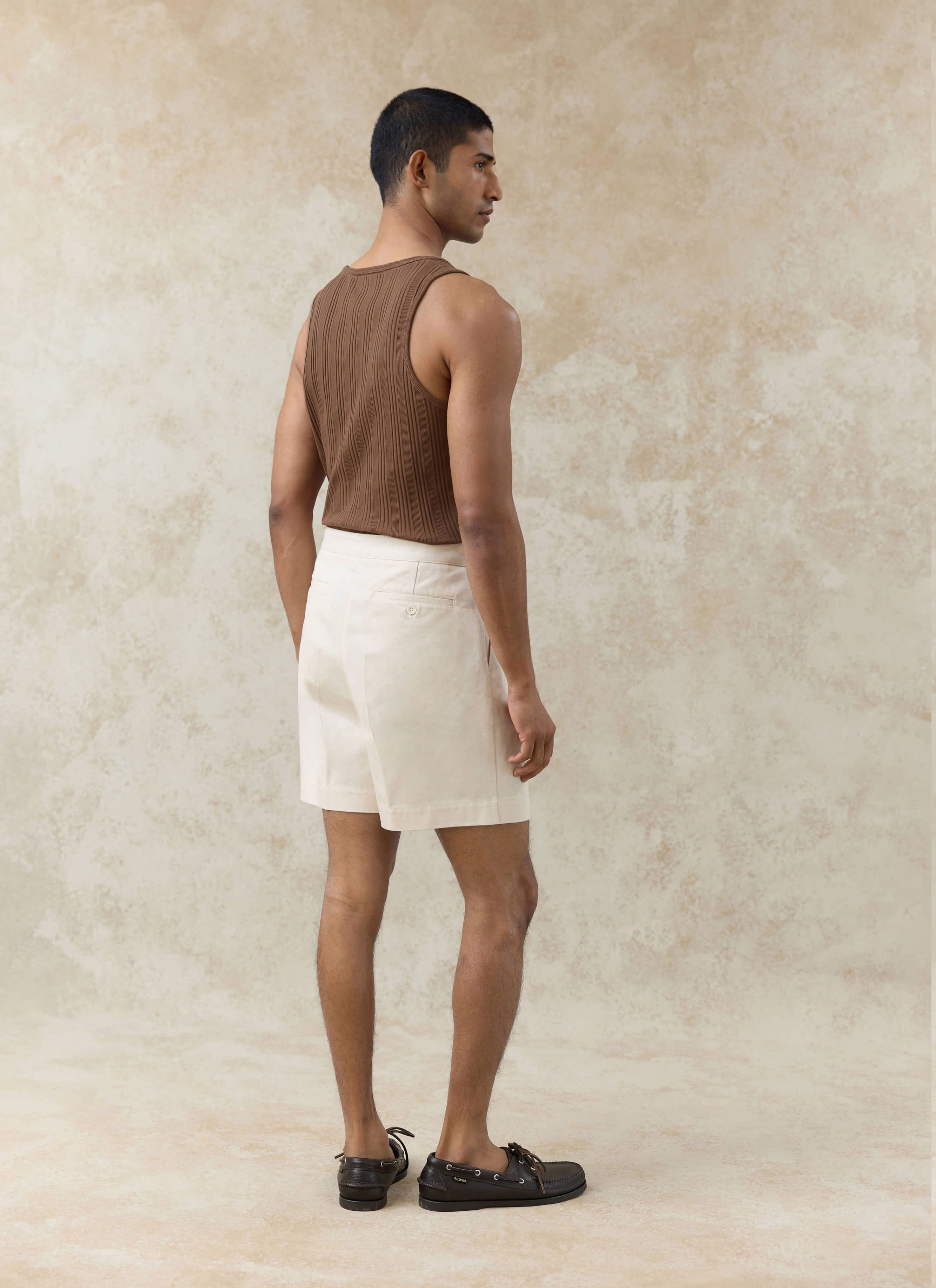 Brown Percival Leon Ribbed Vest in organic cotton, shown from behind with cream shorts and boat shoes.