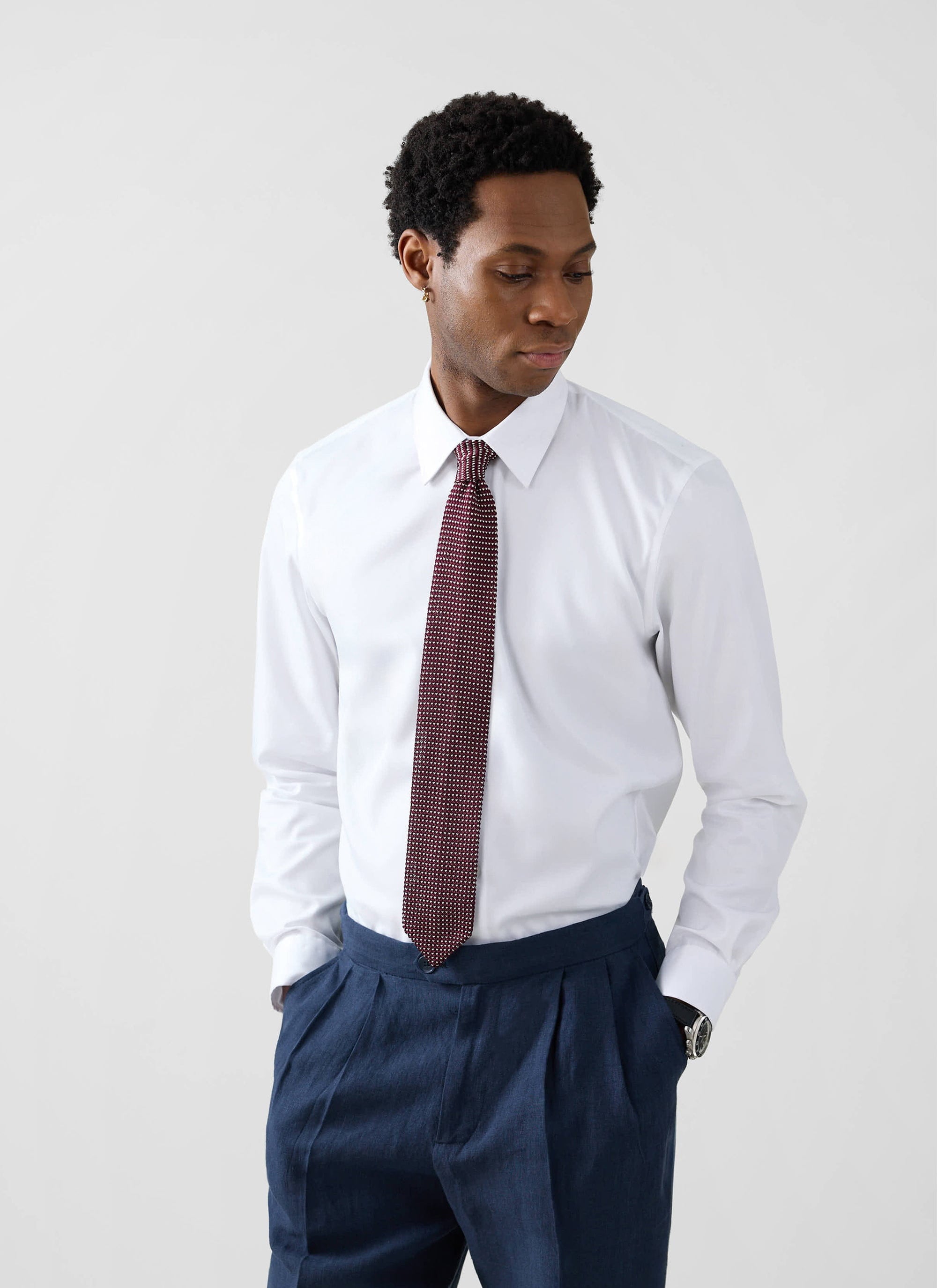 A model styles the Percival Formal Classic Shirt in white with a burgundy patterned tie and smart navy pleated trousers.