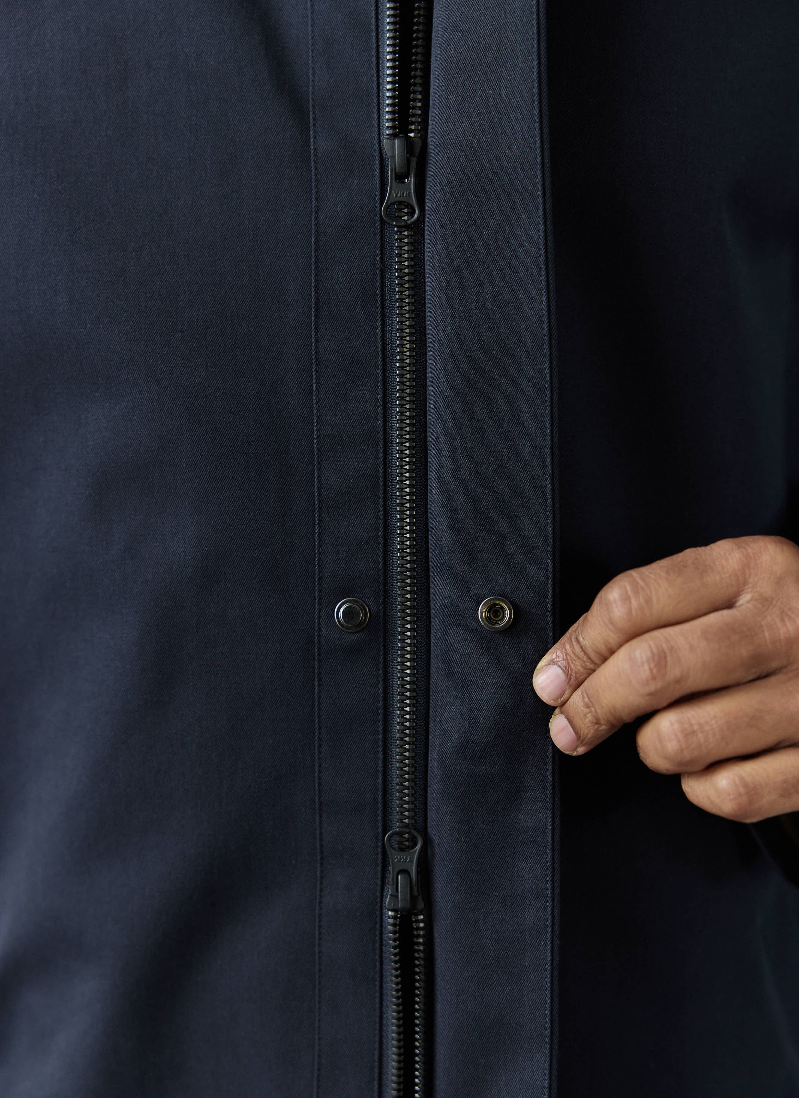 A close-up of the technical zip and snap button closure of the navy waterproof Greyson Trench Coat from Percival.