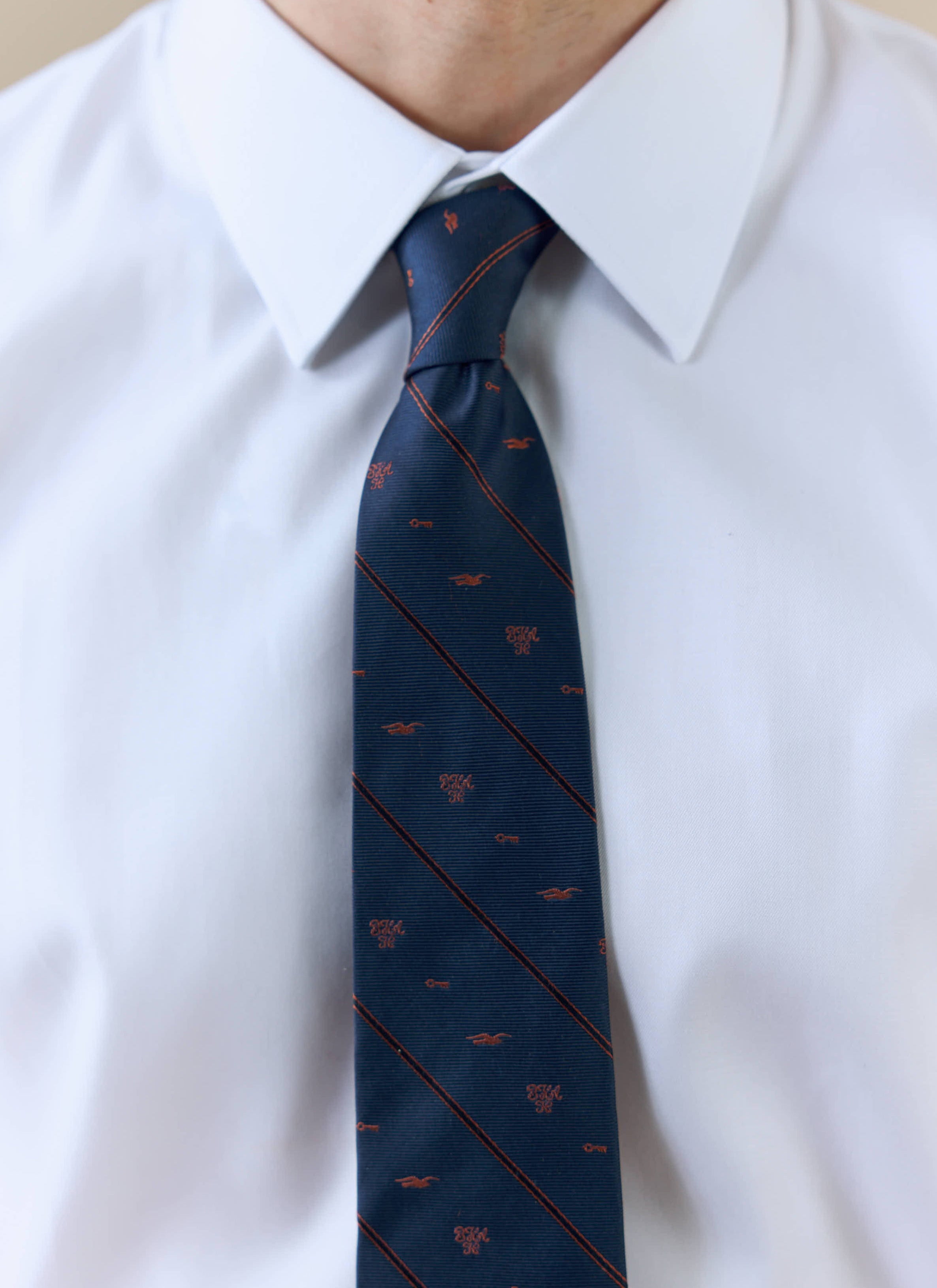 A close-up of a model wearing the Percival x Brighton & Hove Albion F.C. navy silk jacquard tie, showing the stripe pattern.