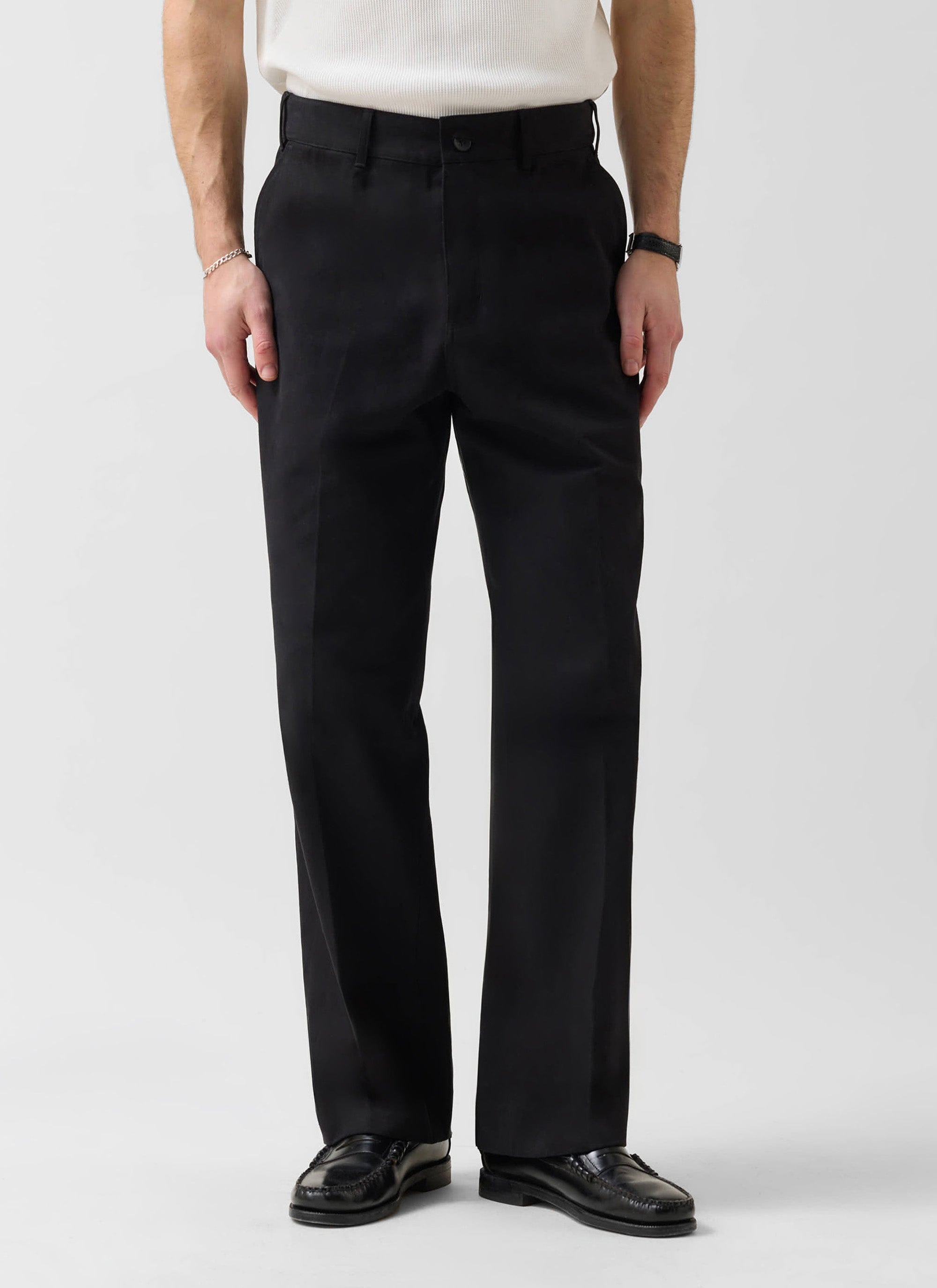 A man models the black cotton Wide Leg Chino from Percival, paired with black loafers against a clean white background.
