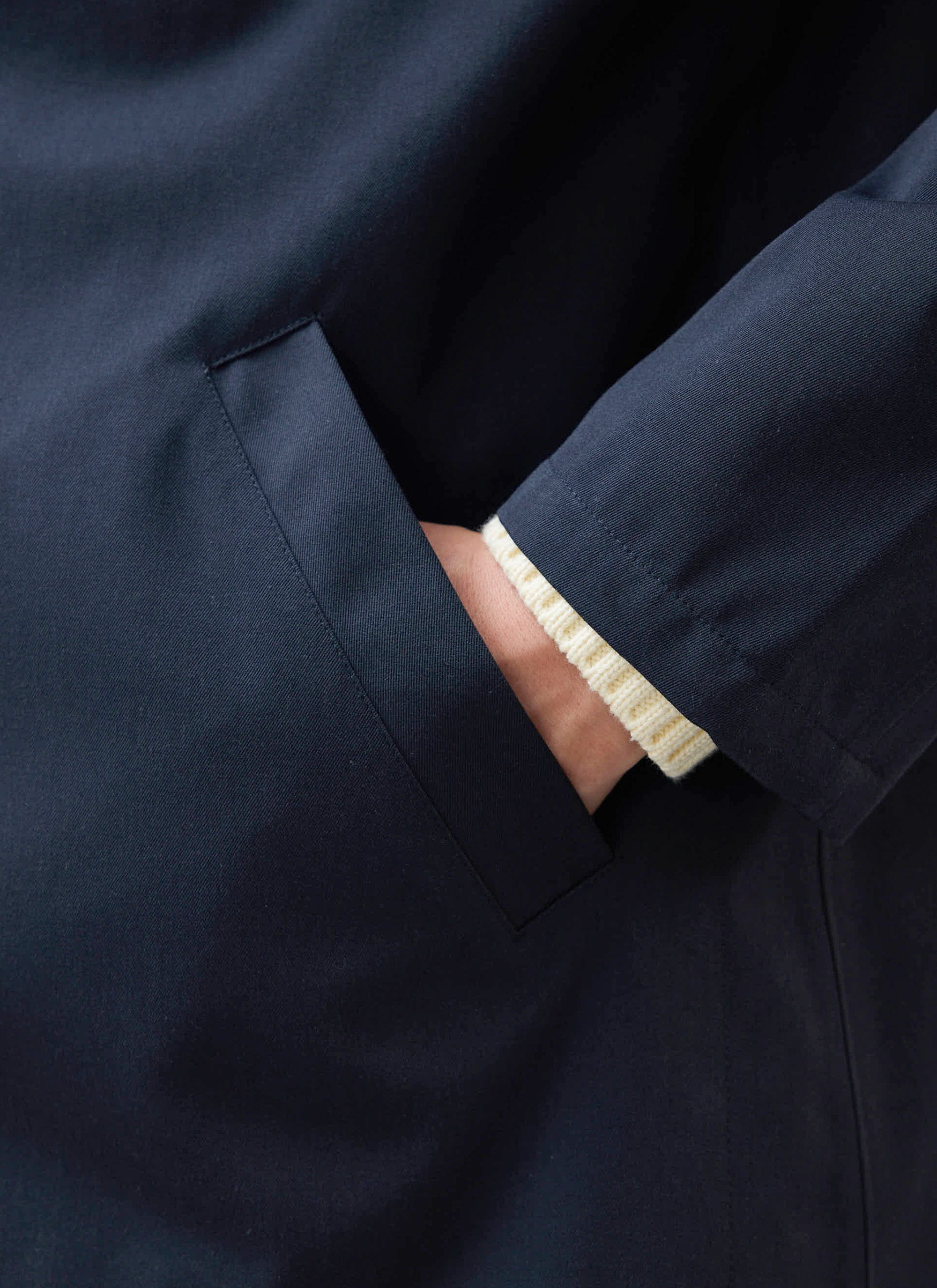 A close-up of the welt pocket on the waterproof Sherlock Short Trench Coat in midnight navy by Percival.